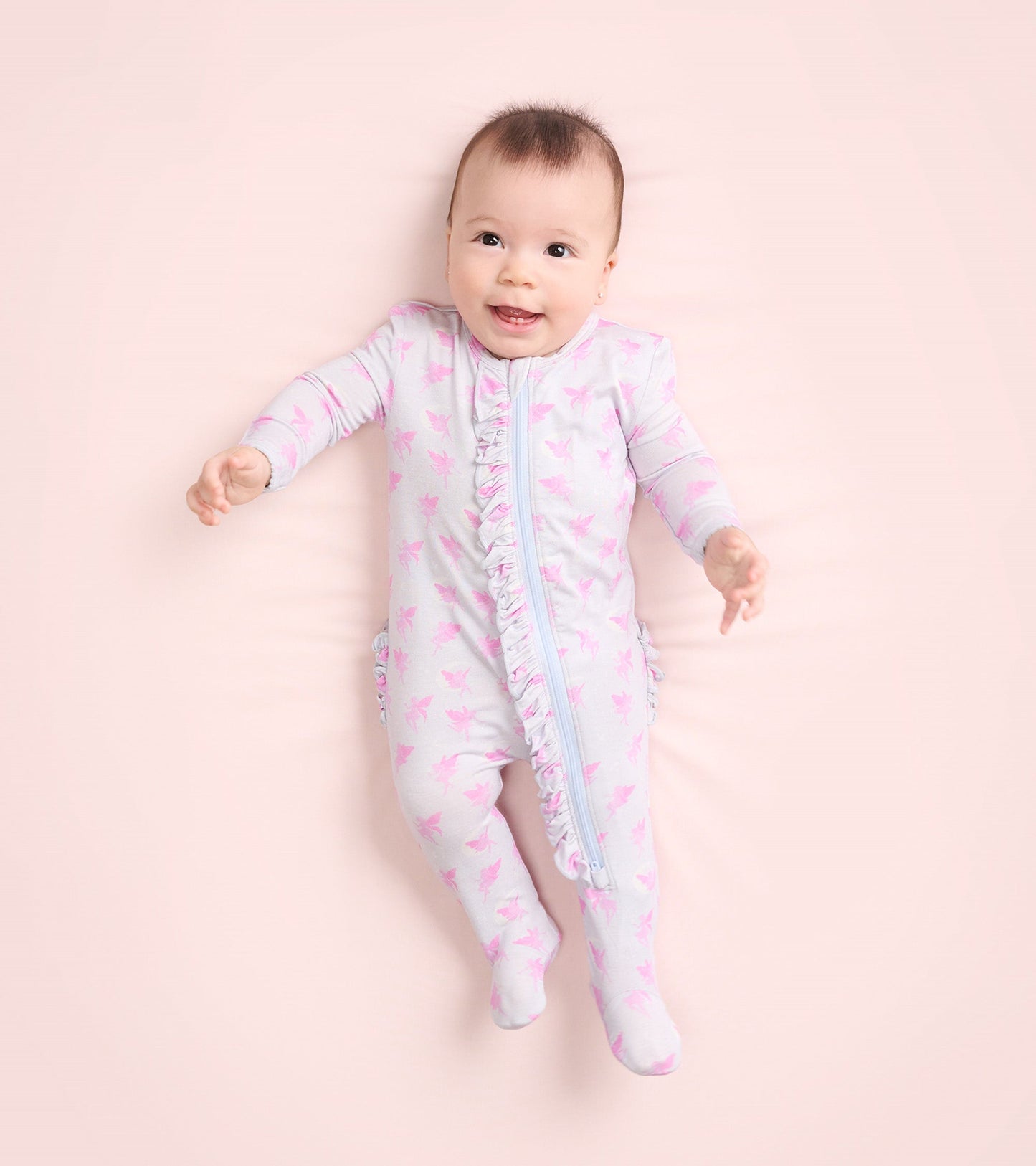 Light gray footed sleeper with pink fairy print and ruffle detail, designed for baby girls, featuring a front zipper.