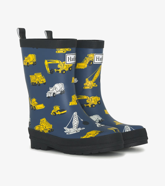 Matte navy rain boots featuring yellow construction vehicle patterns, designed for boys, with textured black soles.