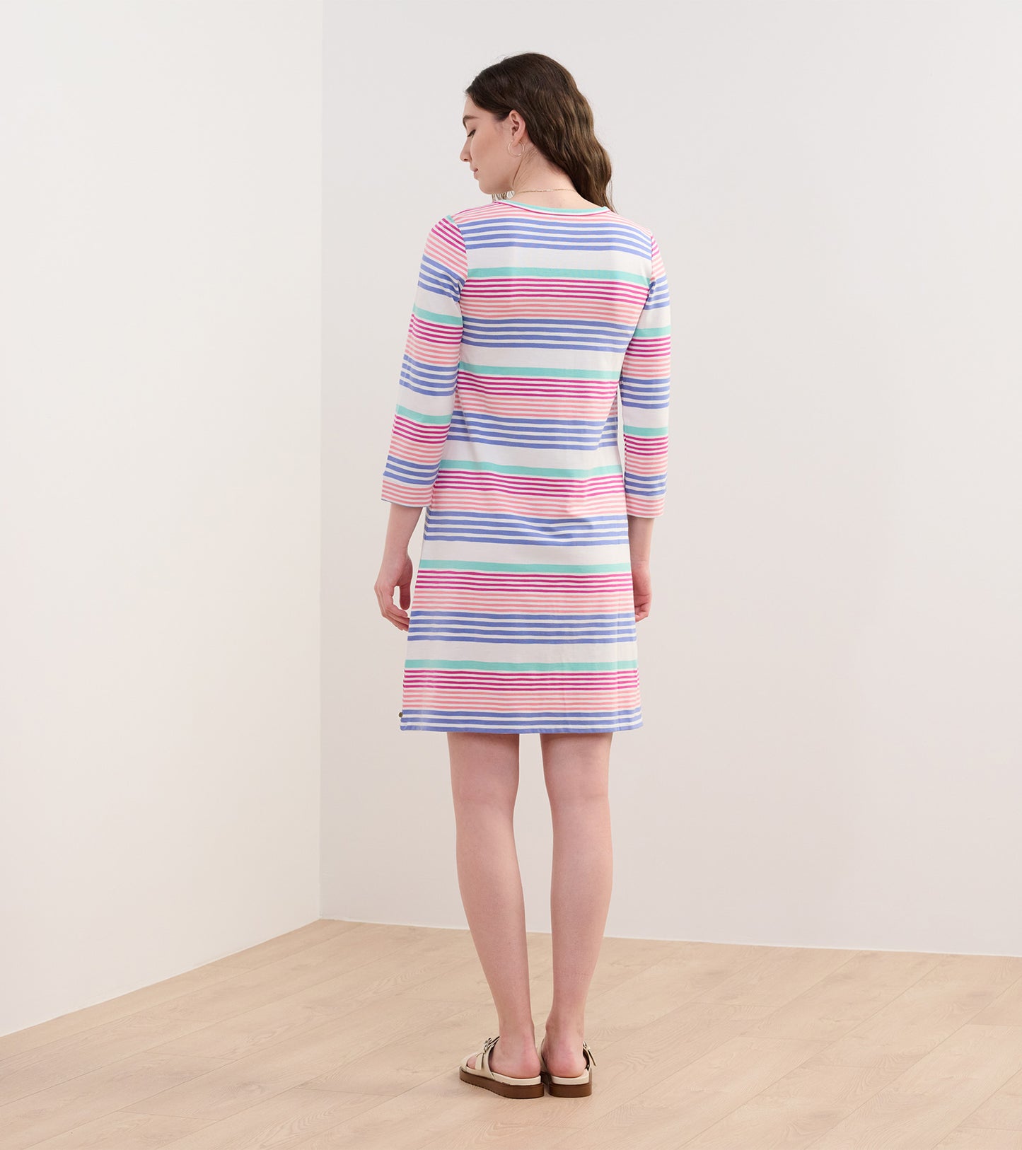 Peach dress with colorful horizontal stripes, featuring three-quarter sleeves and a relaxed fit, shown from the back.