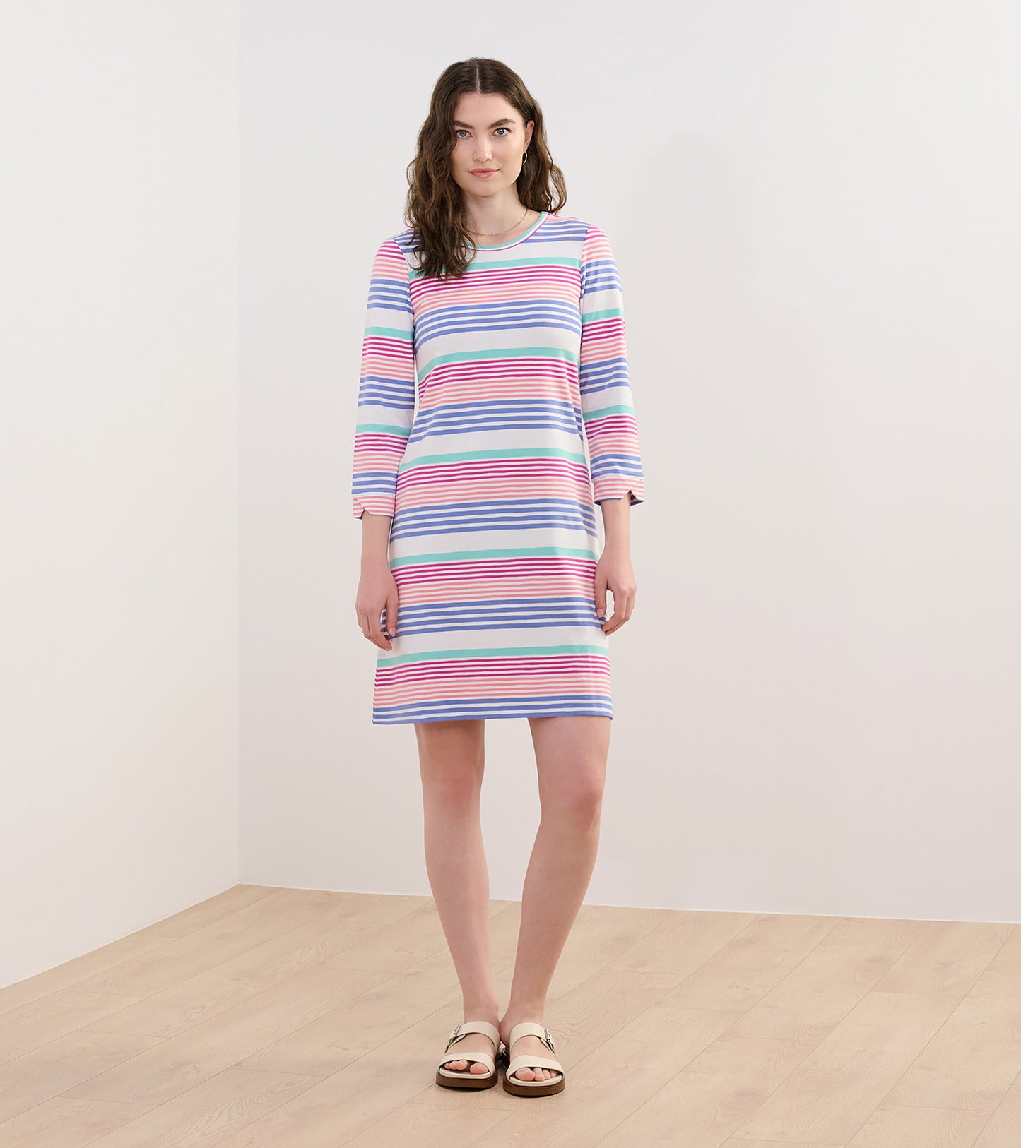 Peach and blue striped flare dress with three-quarter sleeves, knee-length, styled with casual sandals.