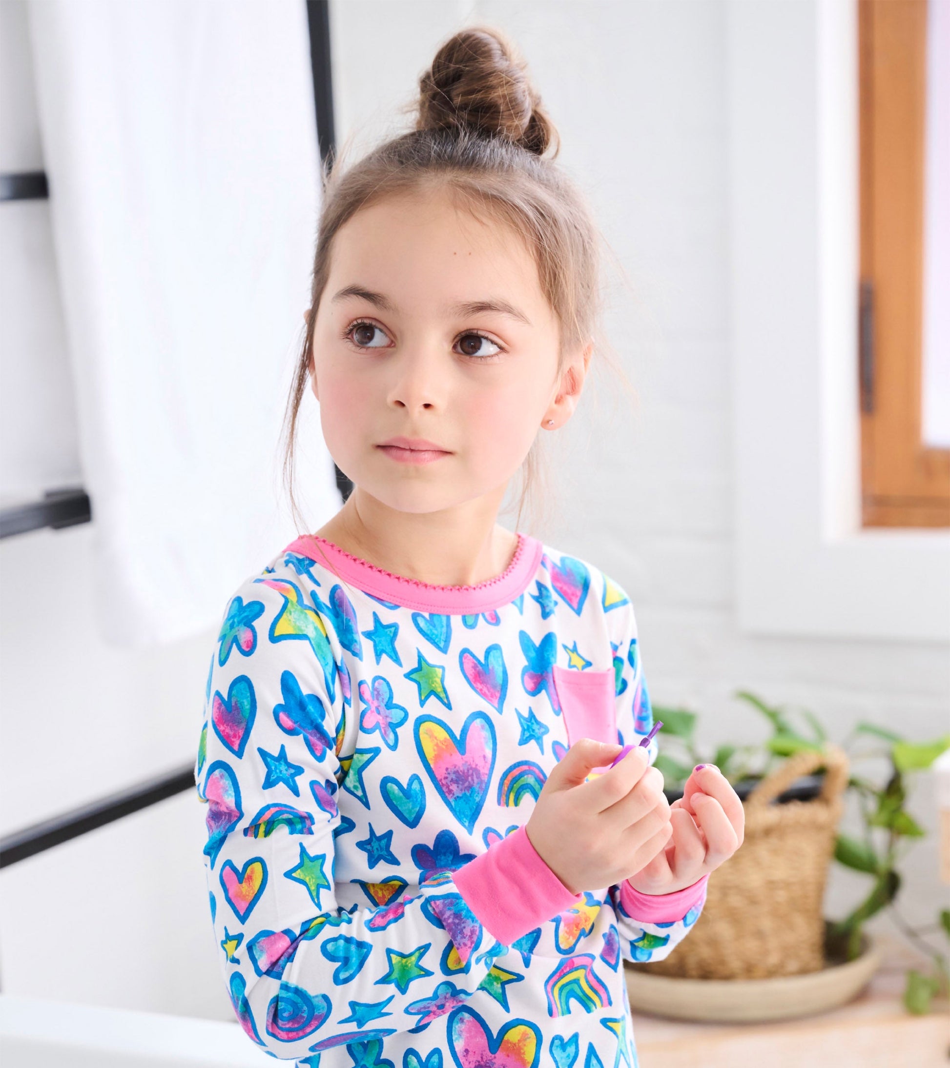 Colorful long-sleeve pajama set featuring watercolour hearts, stars, and rainbows with pink accents.