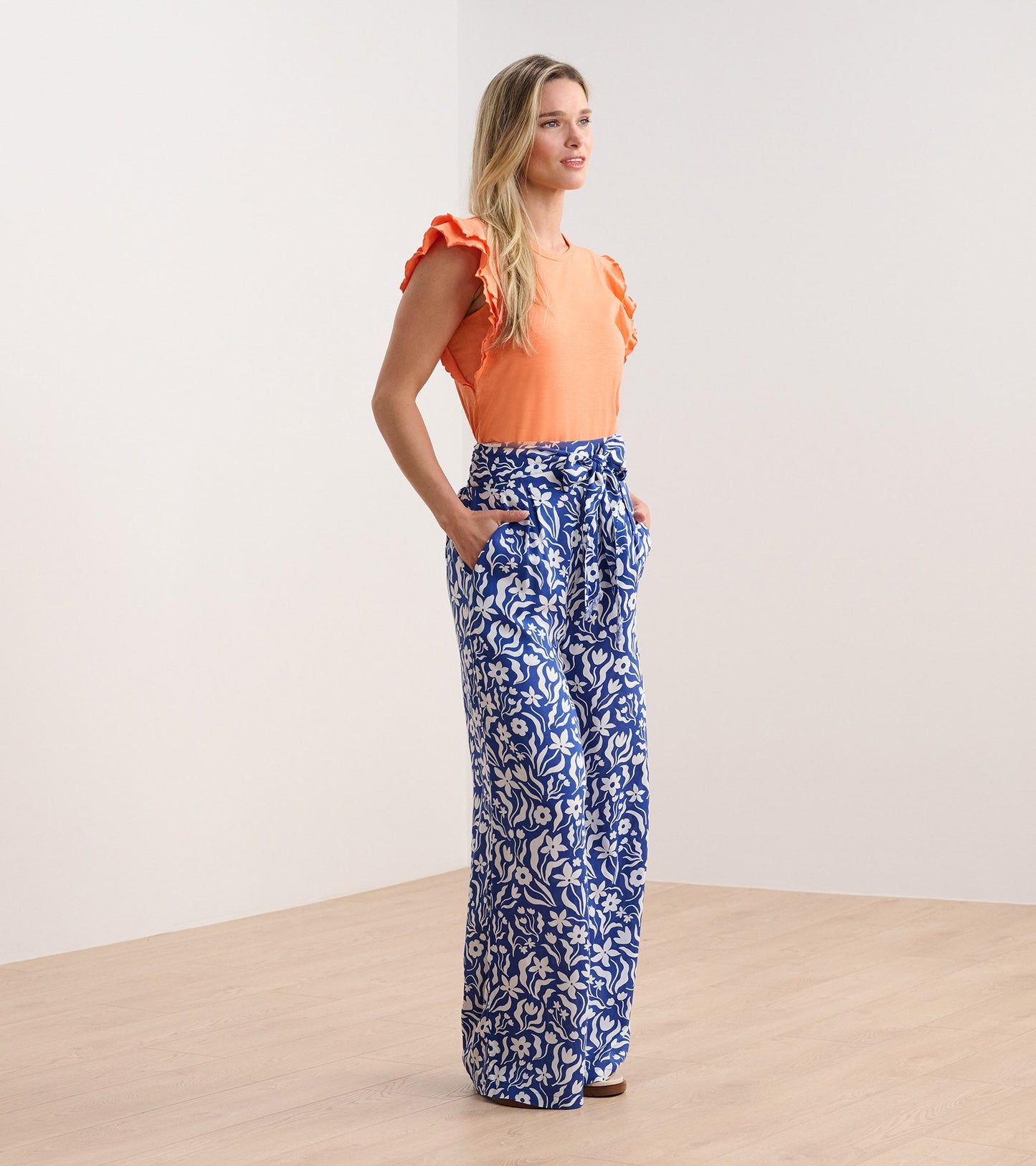 Wide leg pants featuring a blue and white wavy floral pattern, with a belted waist and side pockets.