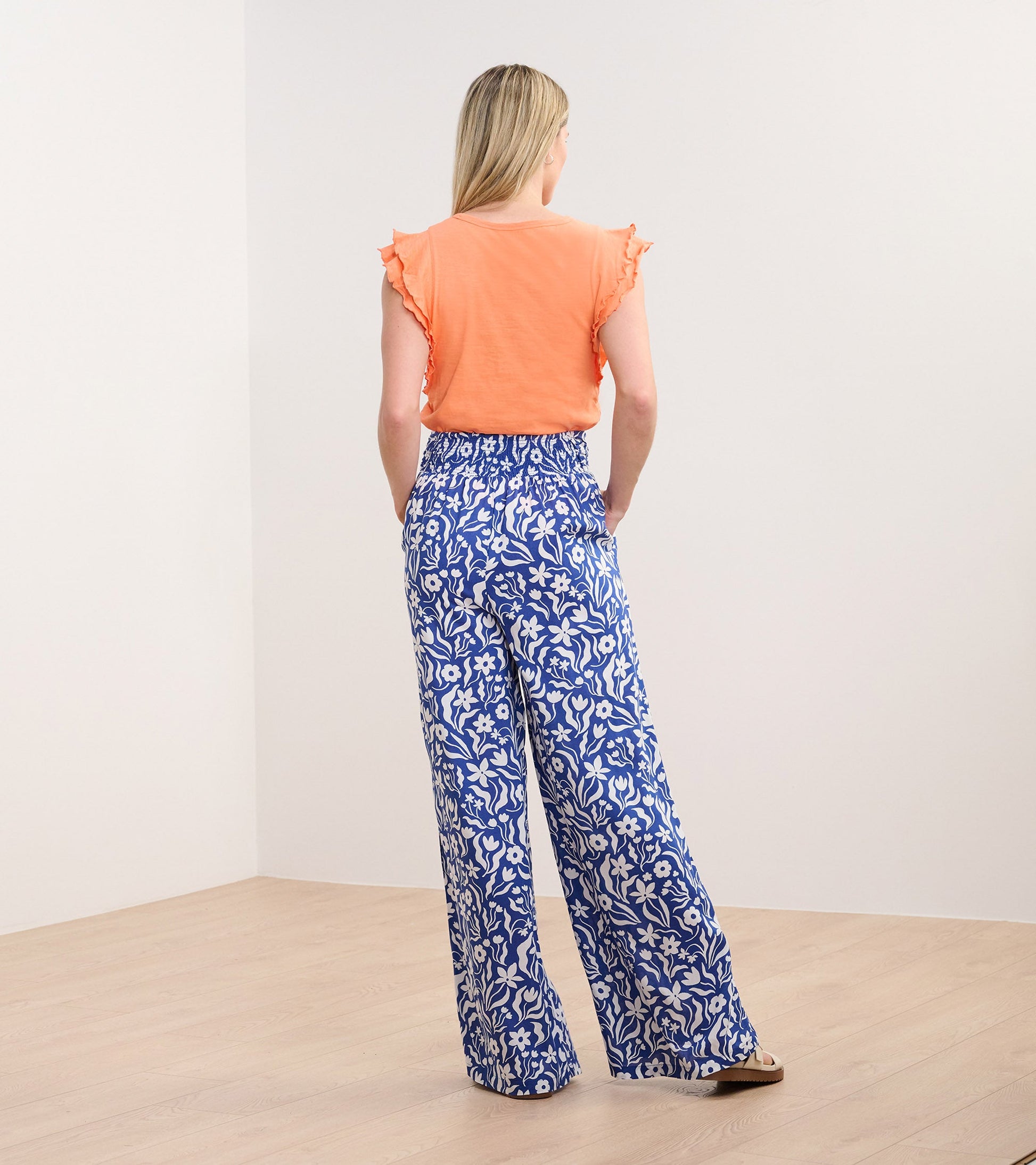 Wide leg pants in blue with white wavy floral pattern, featuring an elastic waistband and side pockets.