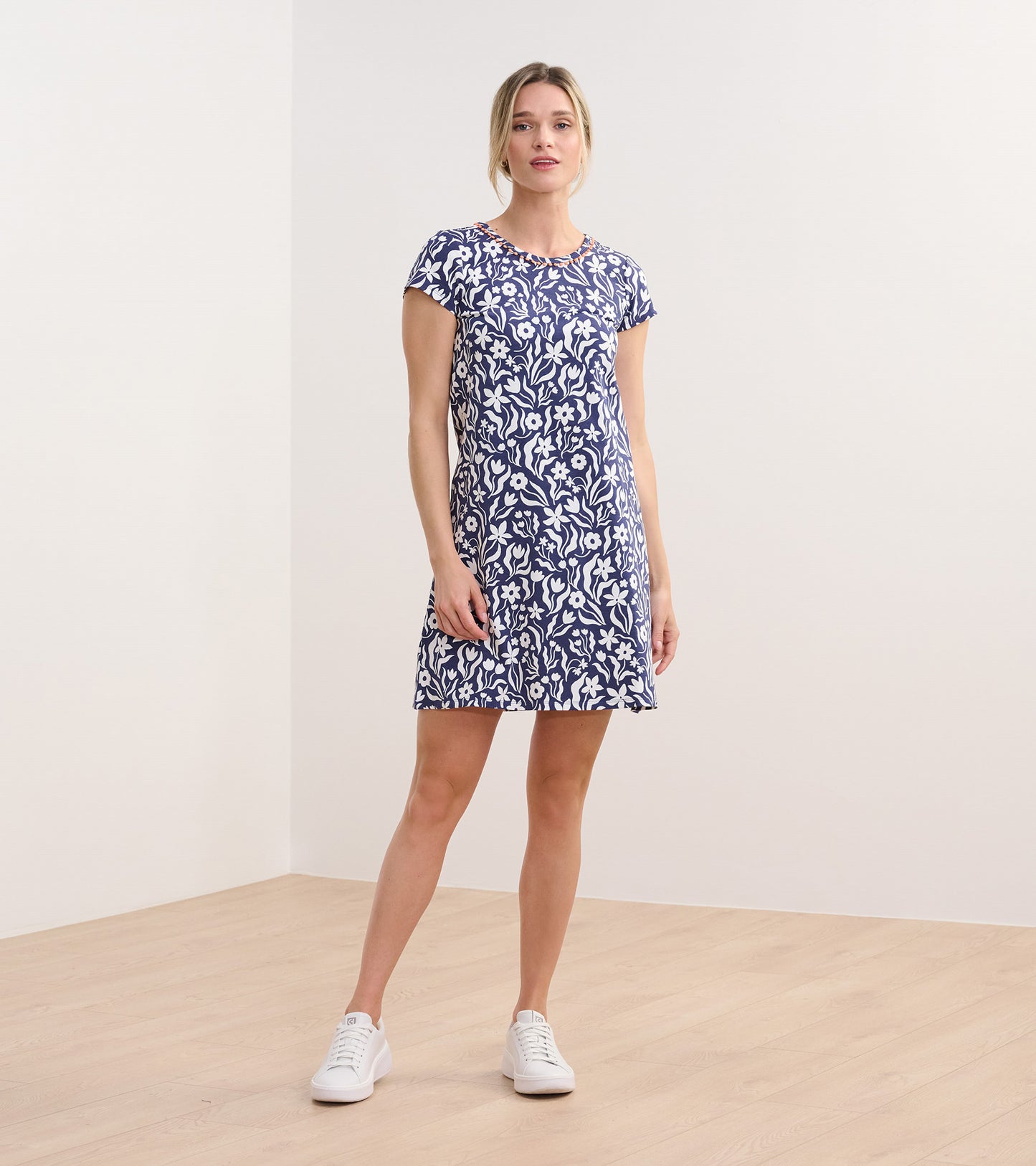 Navy A-line dress with white wavy floral pattern, short sleeves, and a round neckline, styled with white sneakers.