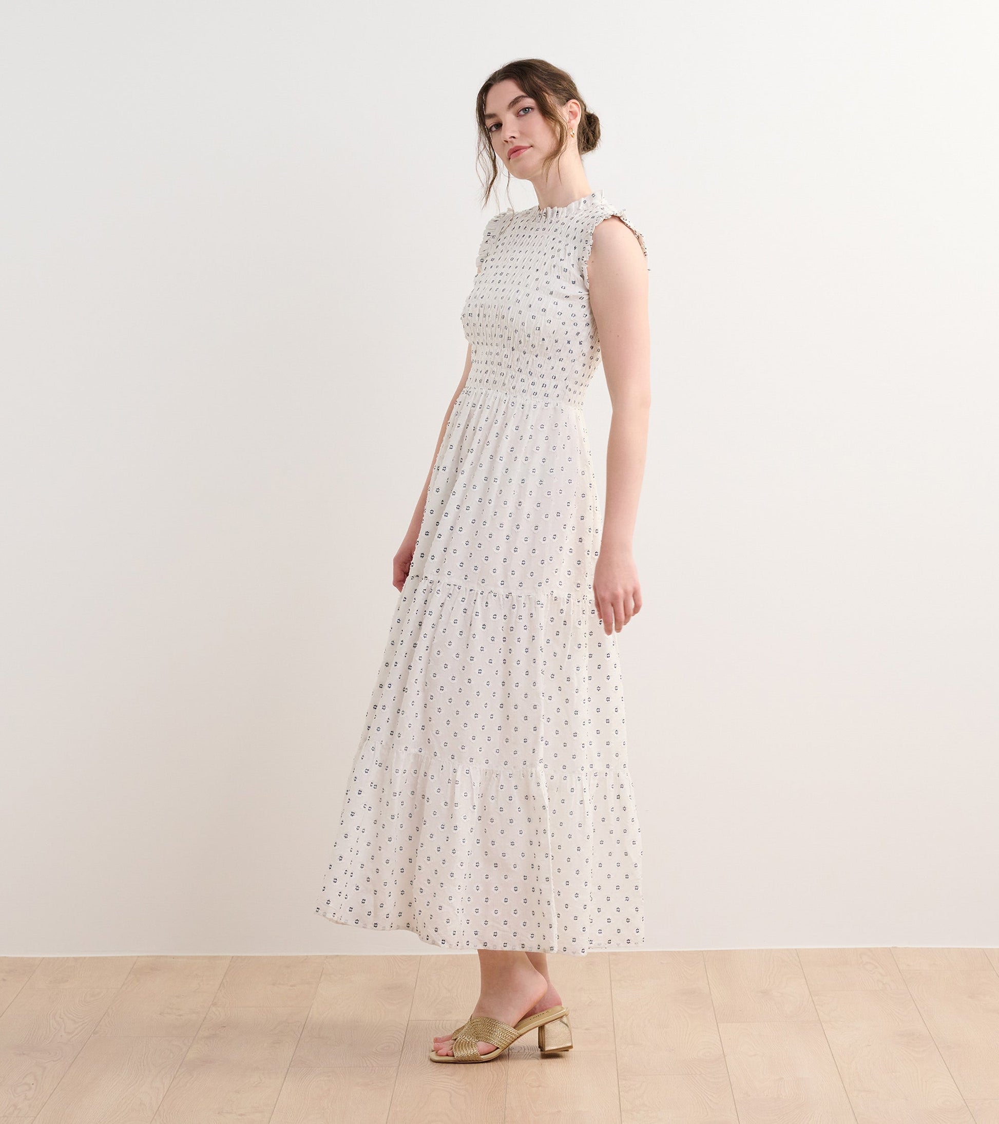 Navy spotted smocked maxi dress with a tiered skirt and cap sleeves, styled with open-toe sandals.
