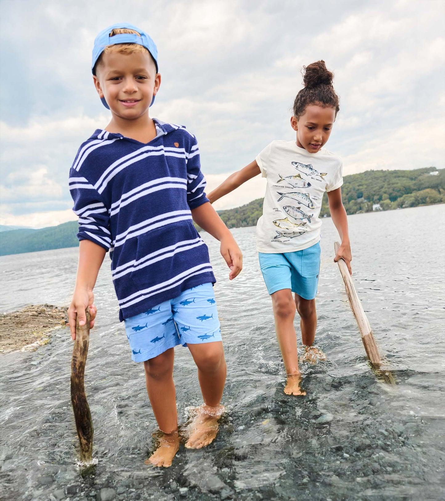 Boy wearing navy striped hooded long-sleeve cover-up, front view, with light blue shorts.