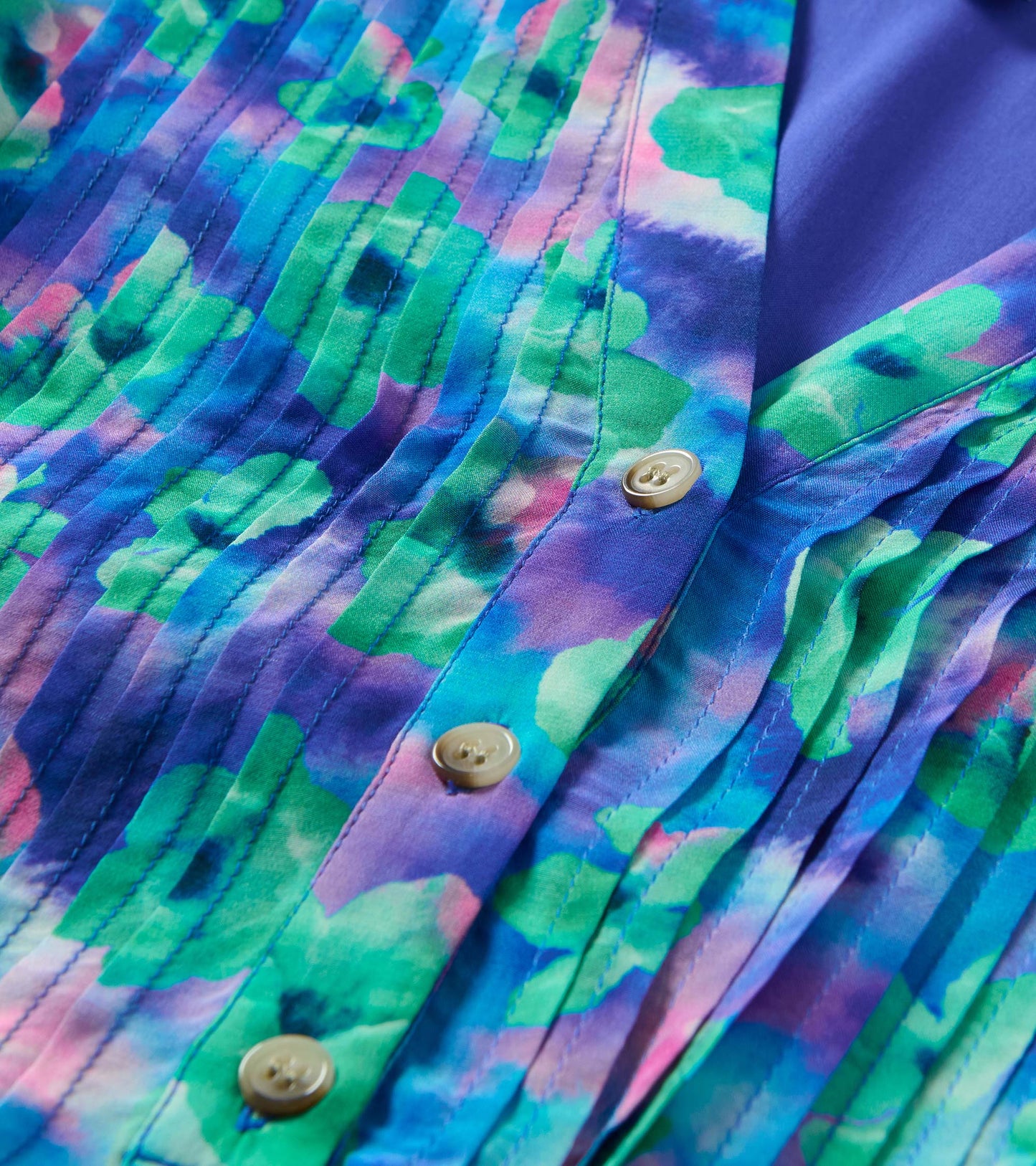 Close-up of blue, teal, and purple floral print with pintuck pleats and button placket detail