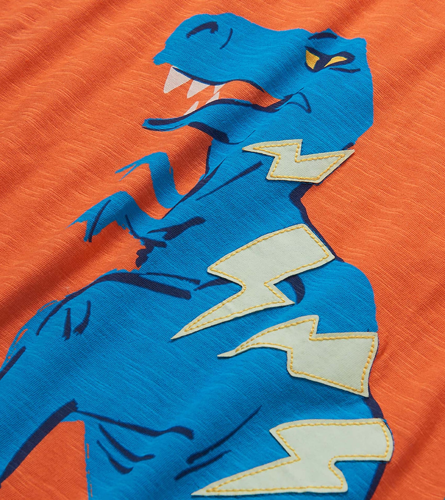 Orange boys T-shirt with blue dinosaur graphic and white lightning bolts, close-up front view
