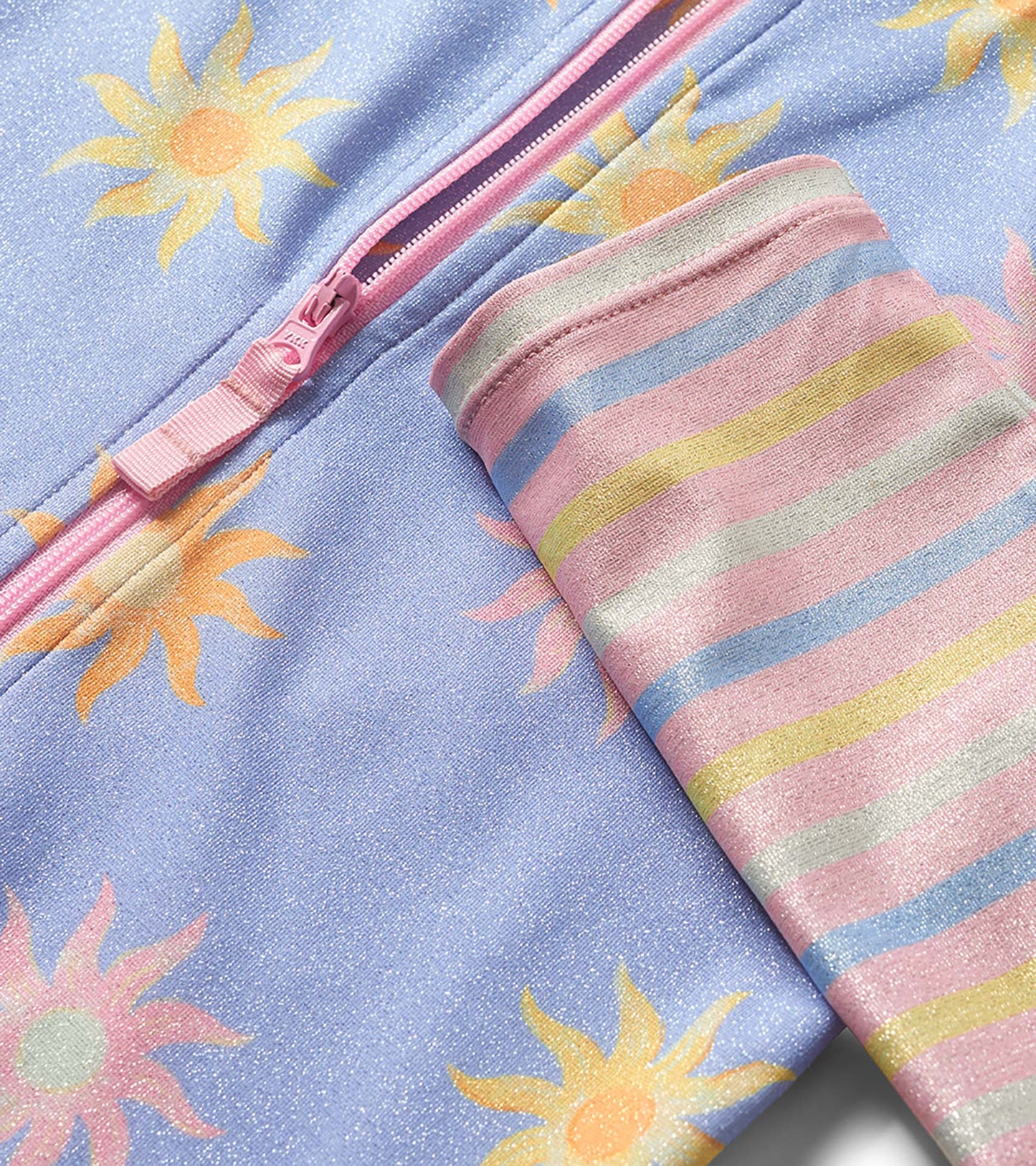 Lavender long-sleeve rashguard swimsuit with sun print, pink zipper, and pastel striped sleeve cuff close-up