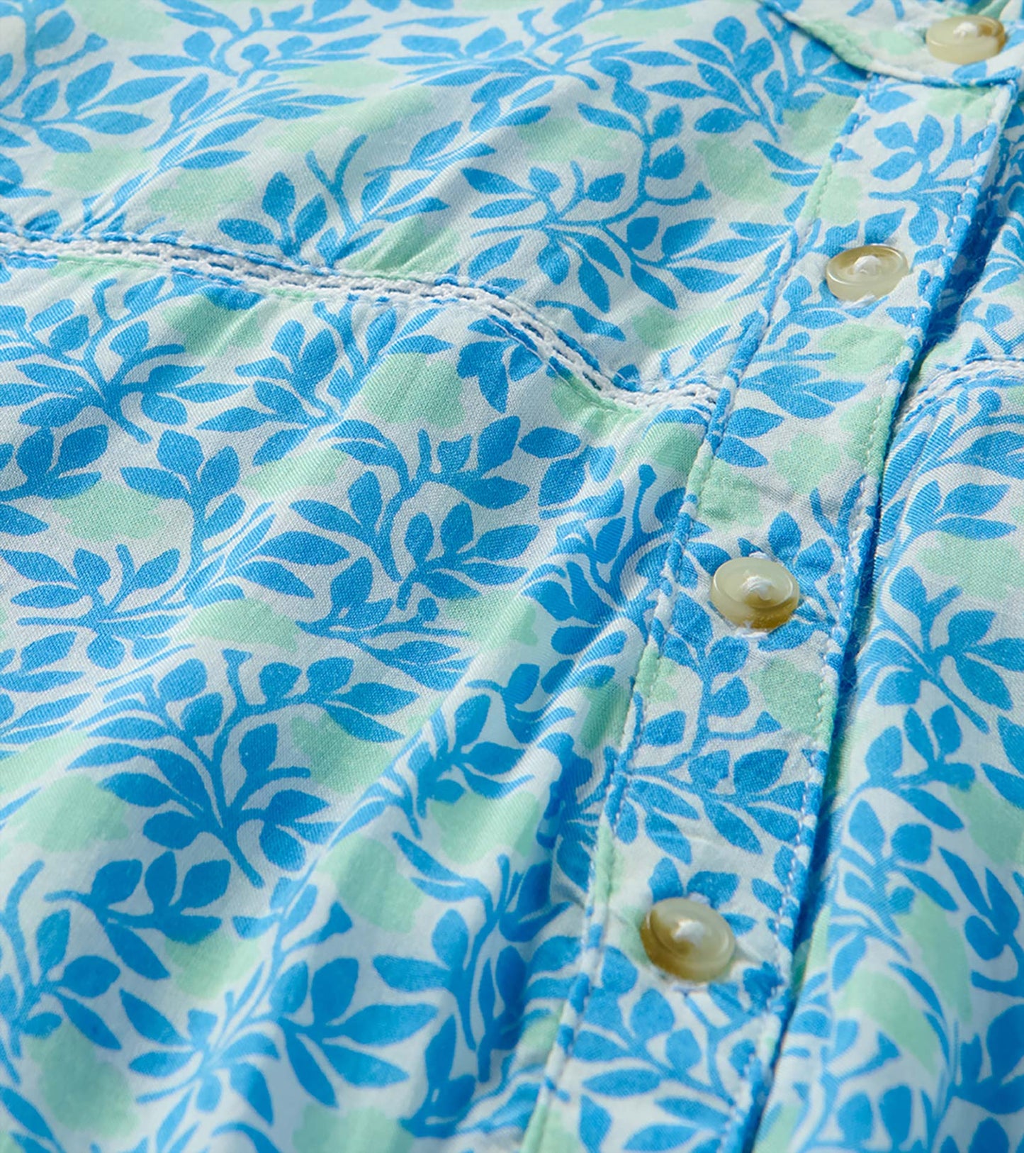 Close-up of blue and soft green mini vine print with button placket and stitched seam detail