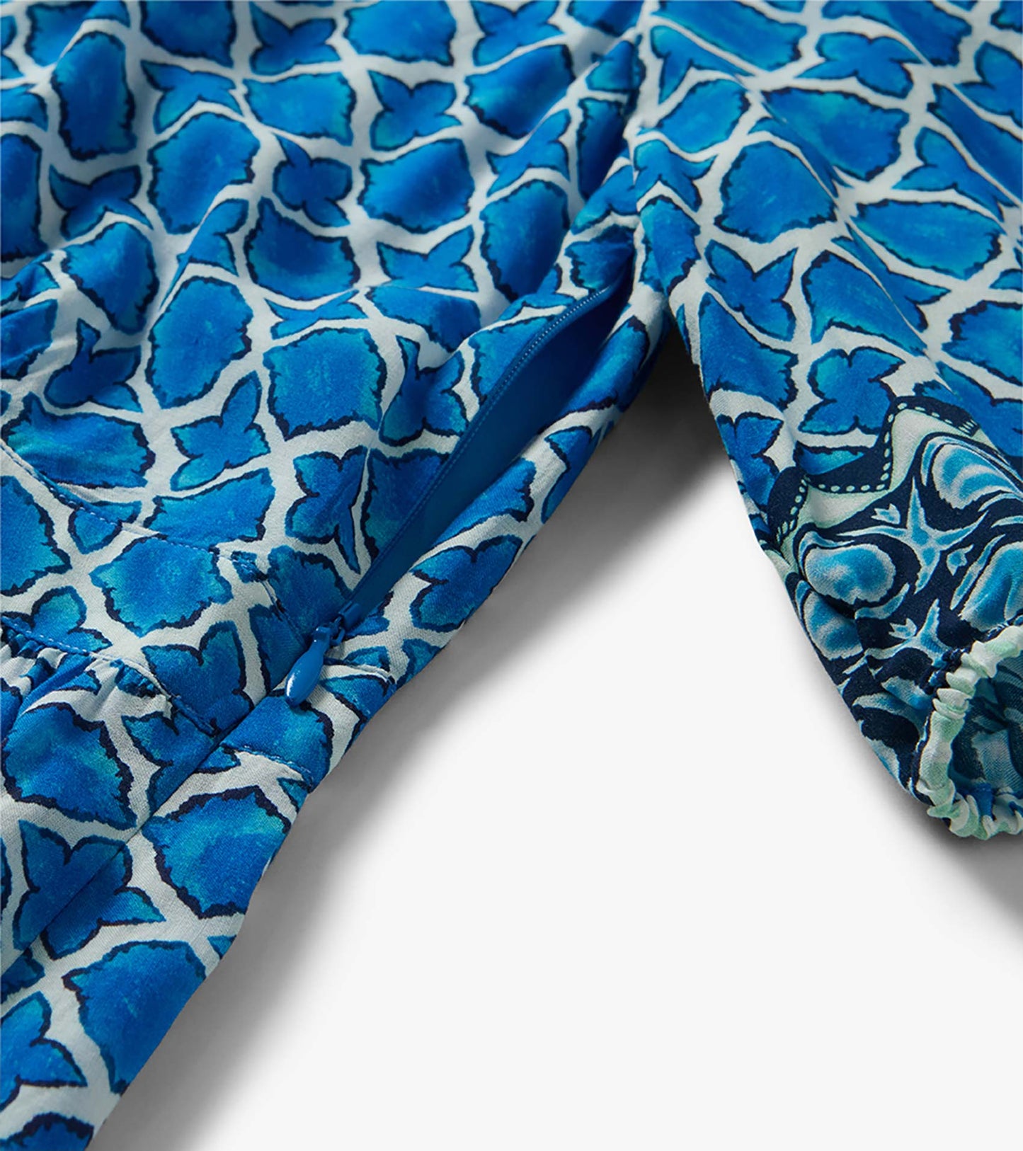 Blue floral patterned dress fabric with zipper detail and gathered sleeve cuff, close-up view