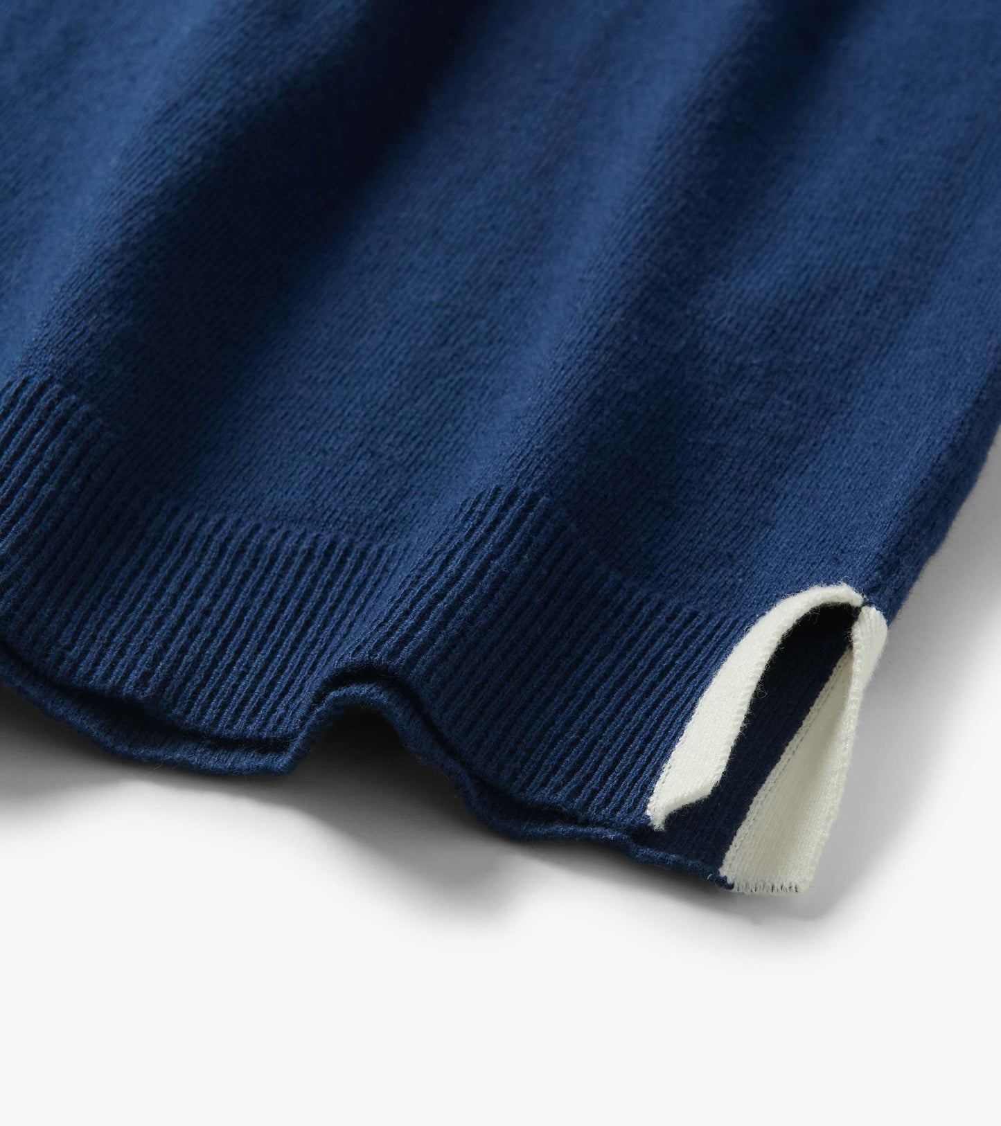 Close-up of a navy blue knit top hem with ribbed trim and a white cuff edge