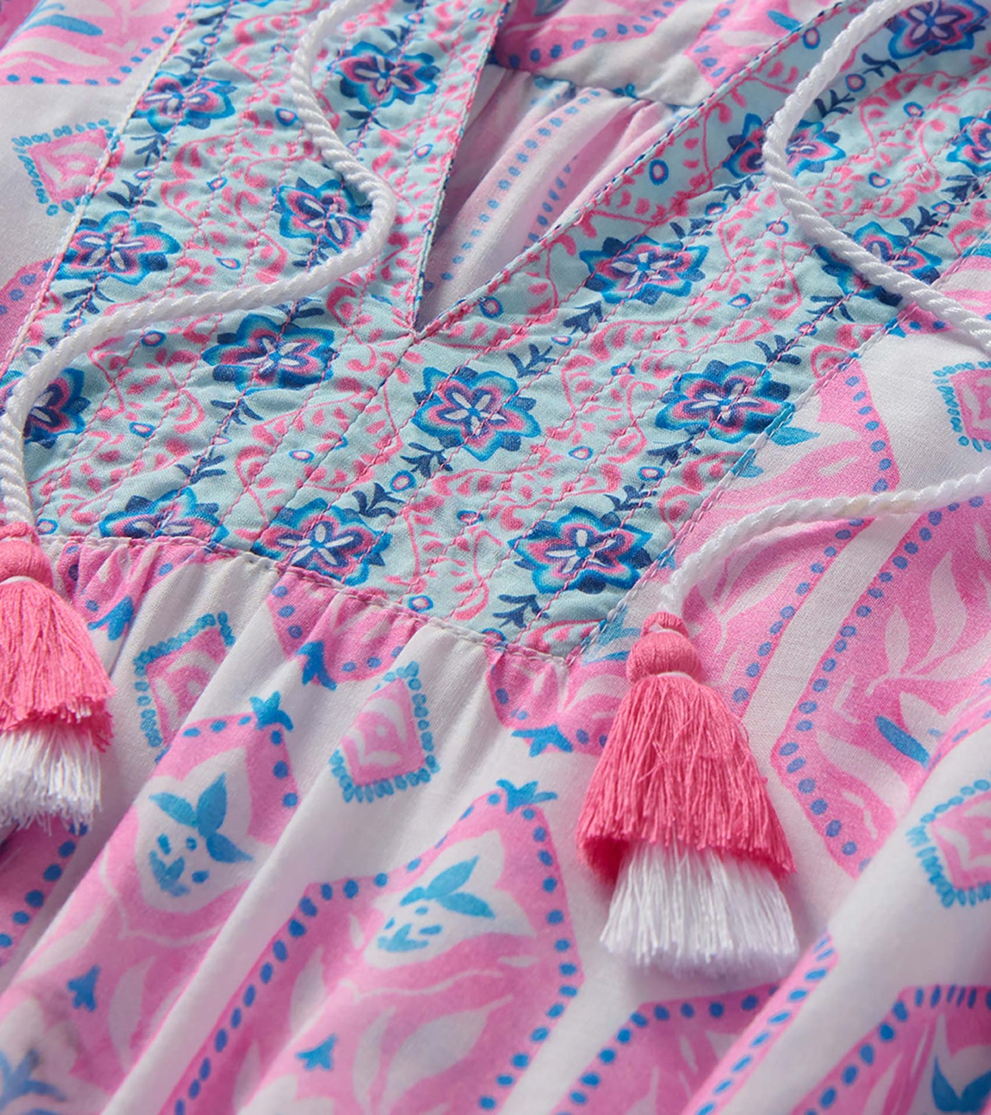 Close-up of the Chloe Dress bodice with pink and blue floral print, stitched paneling, and tassel ties