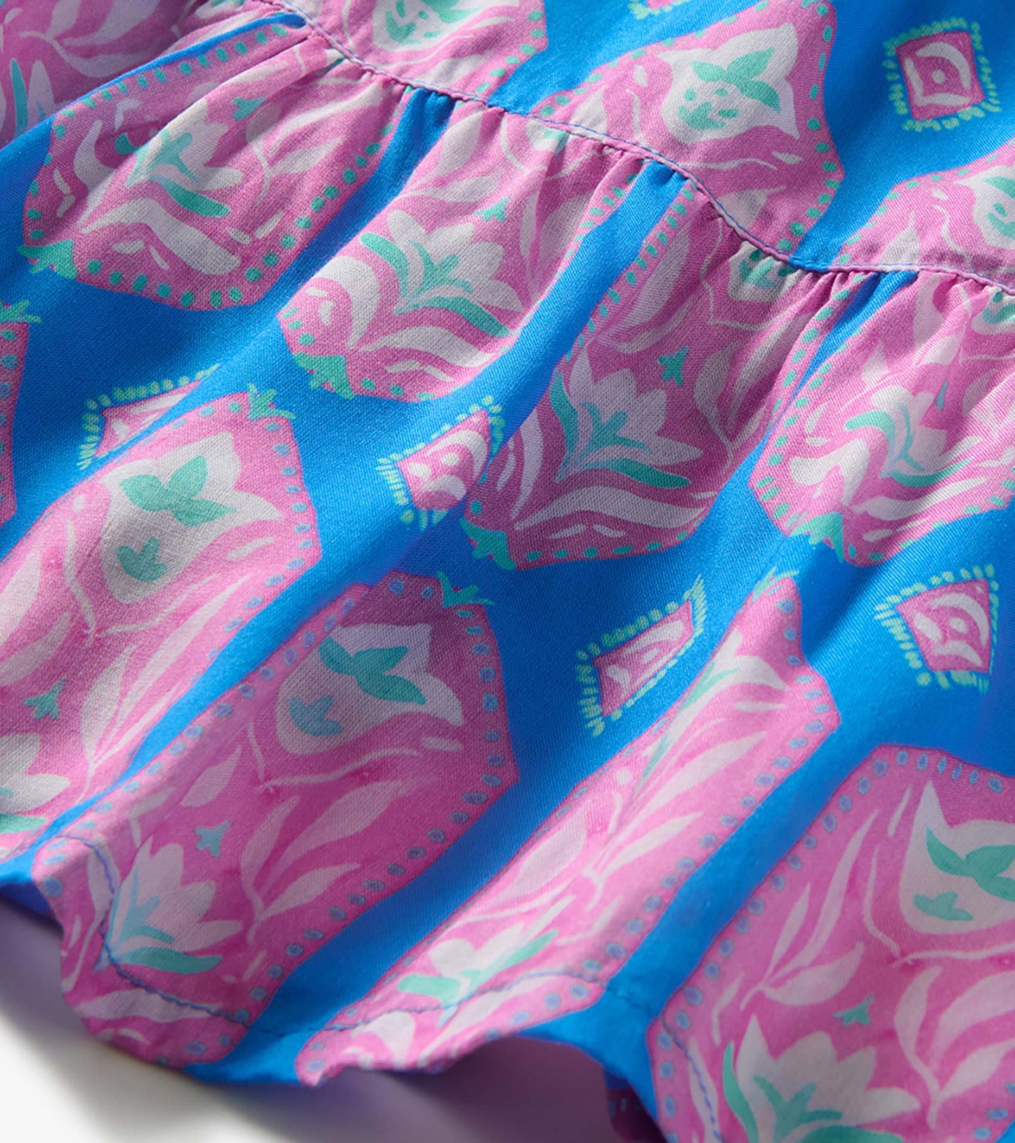 Close-up of blue fabric with pink and mint pressed-flower print and gathered seam detail