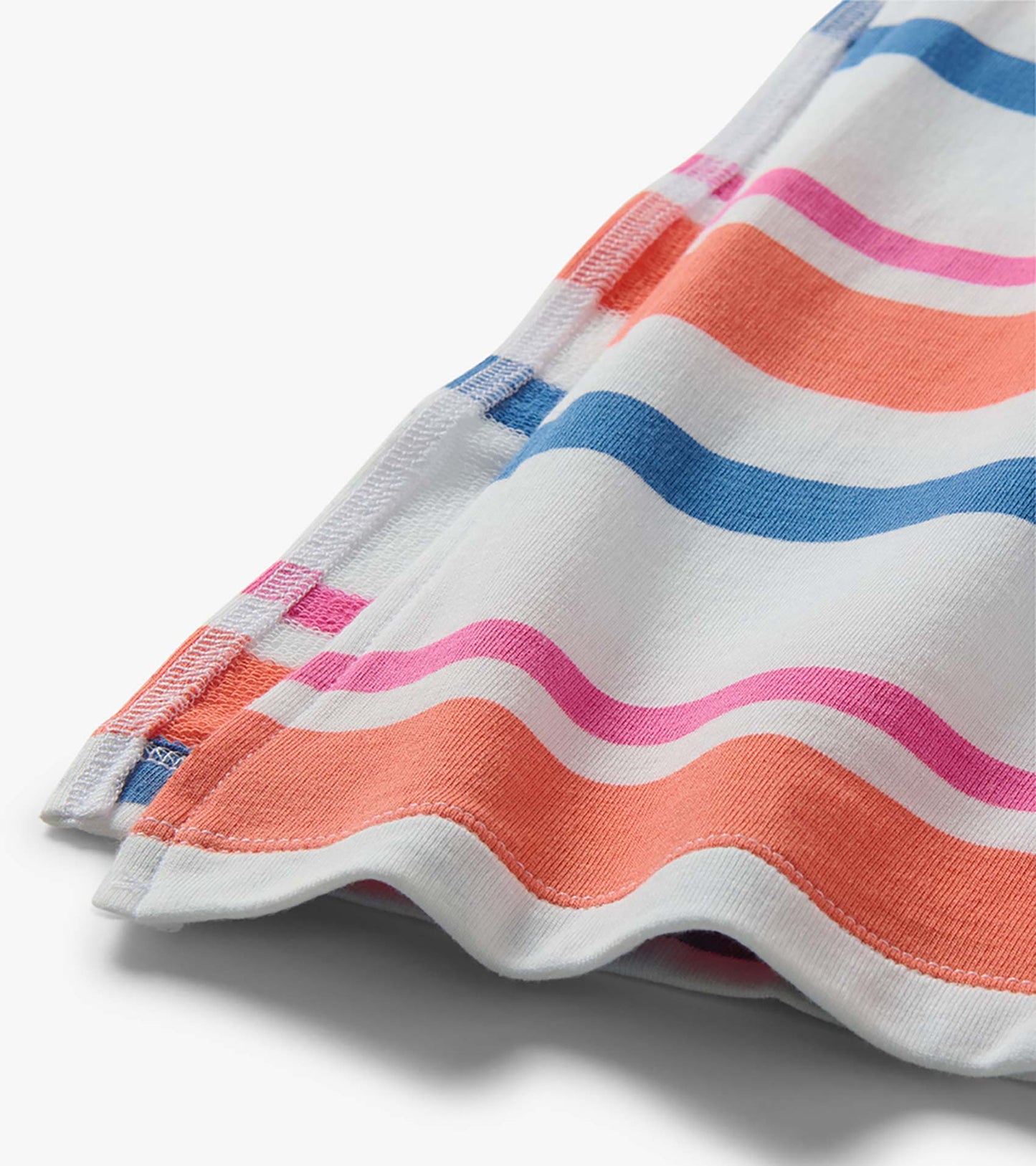 Close-up of a white pleated midi dress with colorful horizontal stripes and wavy hem detail