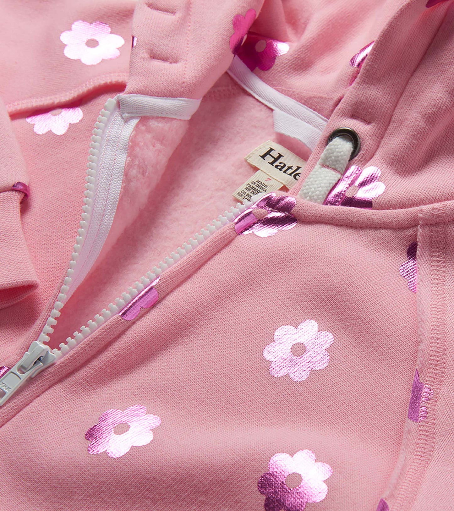 Pink girls zip-up hoodie with white floral print and drawstring hood, close-up view