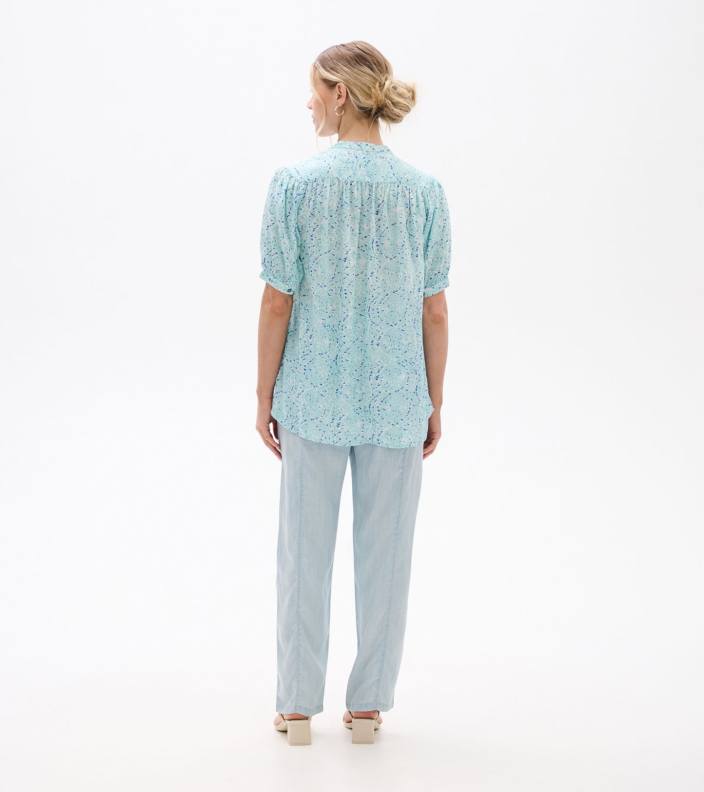 Back view of a light blue ikat-print blouse with short sleeves and a relaxed fit