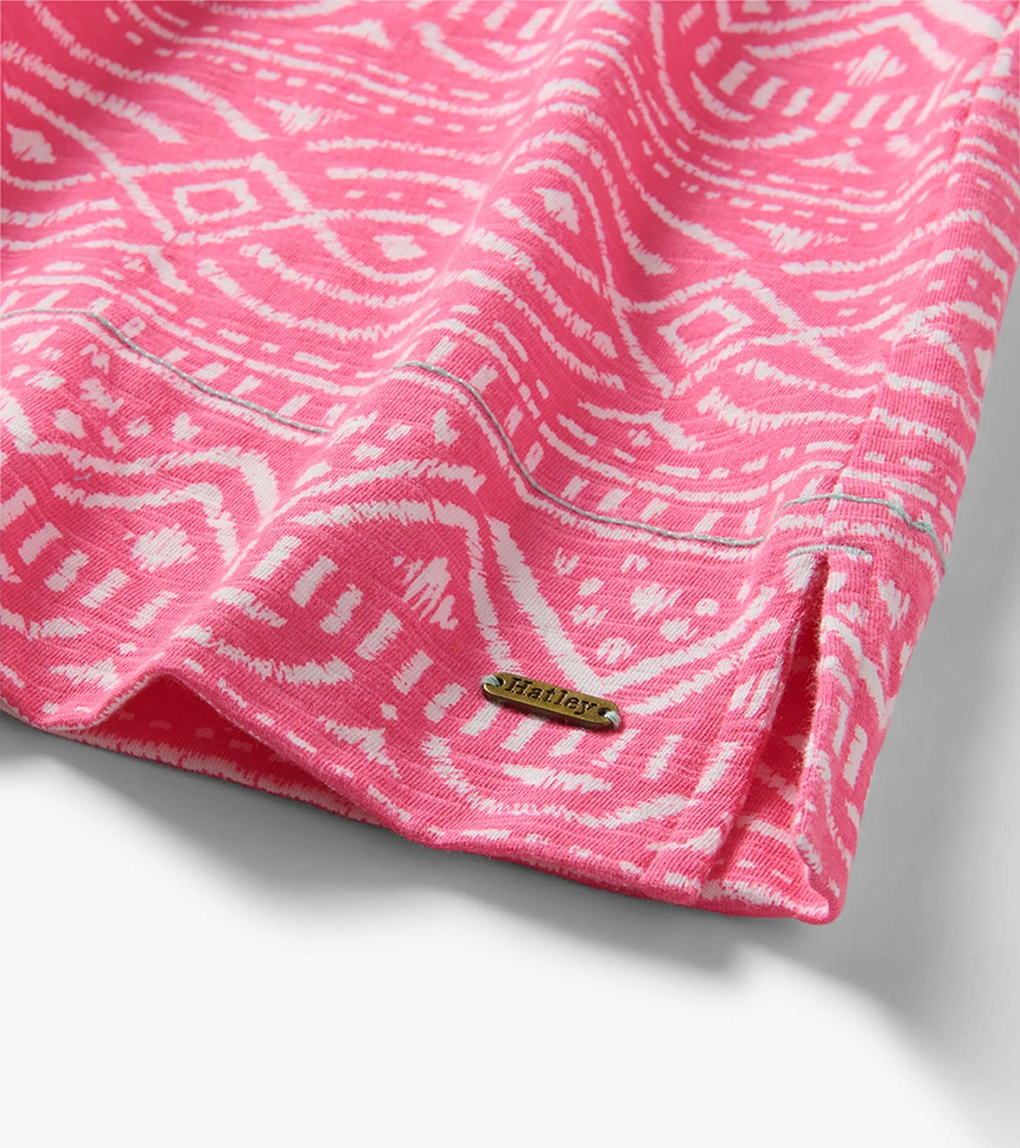 Pink and white patterned knit dress hem with side slit and small metal logo plaque