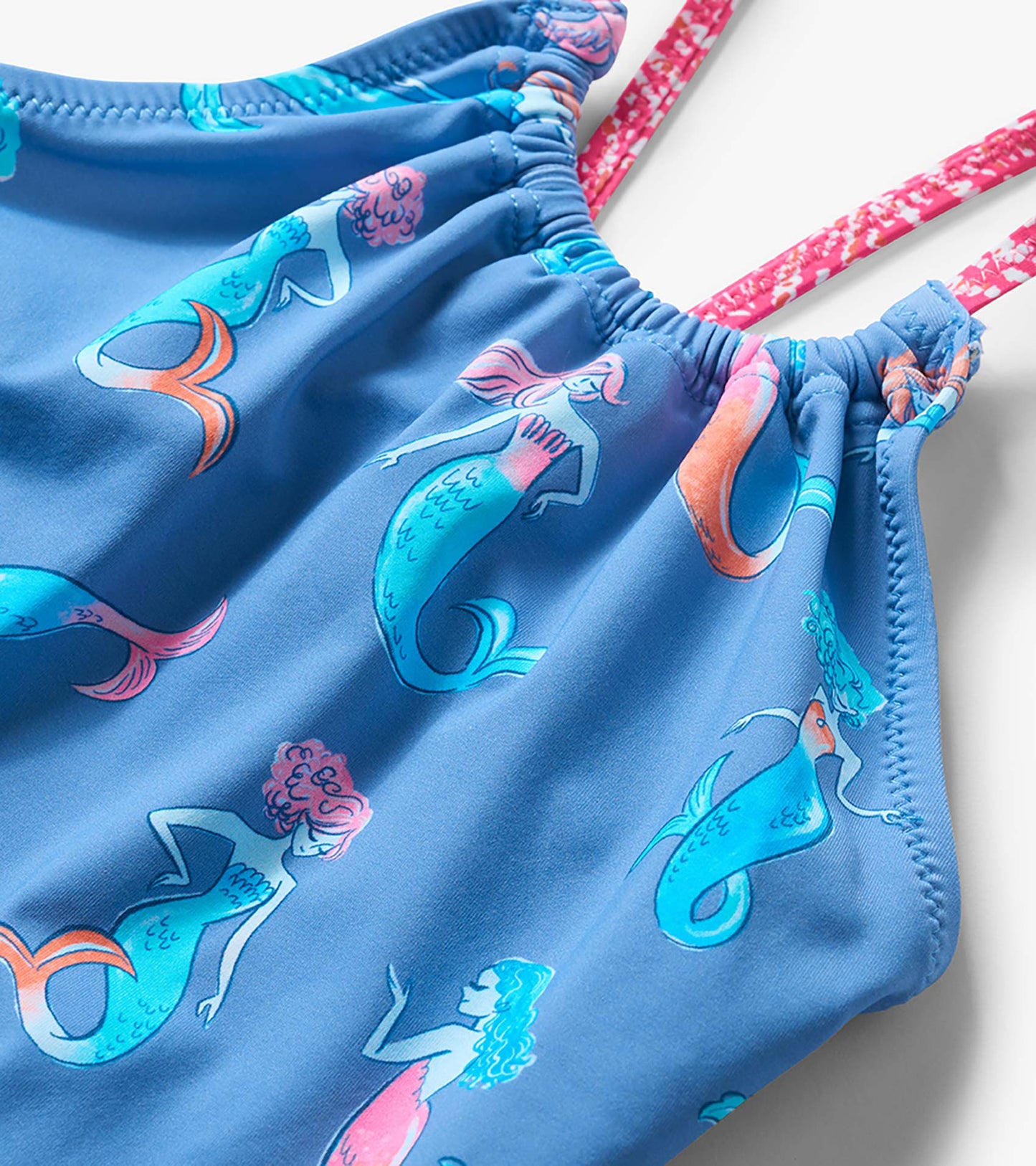Blue girls one-piece swimsuit with colorful mermaid print and pink patterned straps, close-up view