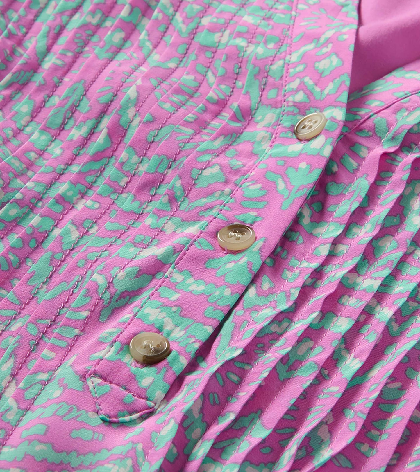 Close-up of Soft Ikat dress with pink and aqua print, pintuck pleats, front buttons, and tie detail