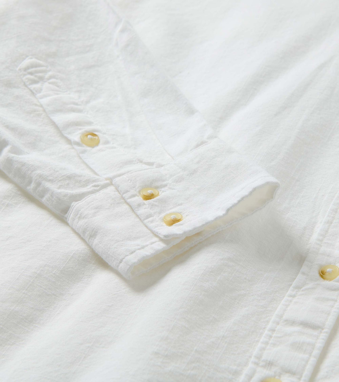 Close-up of the white button-down shirt cuff and placket with pale buttons