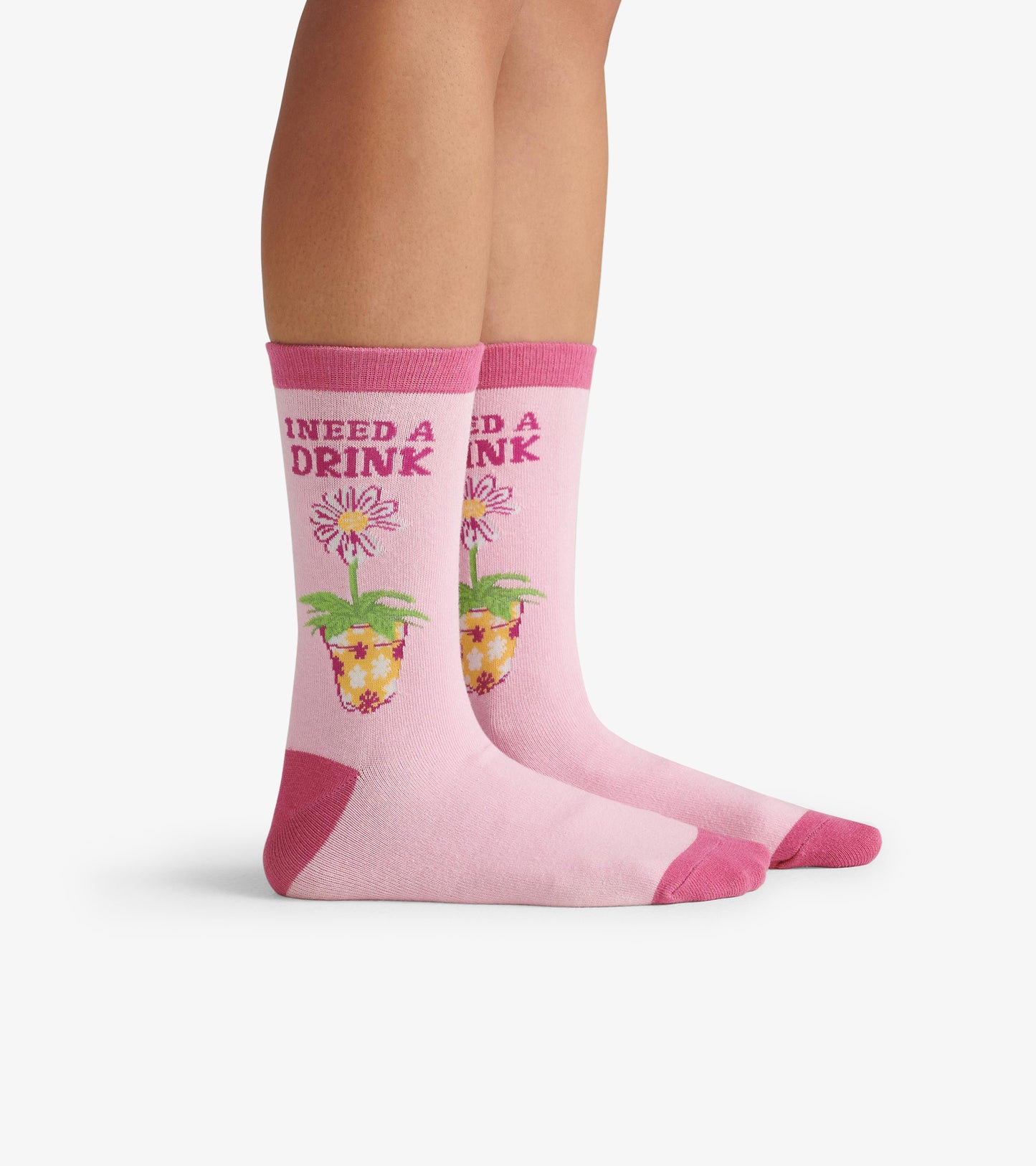Pink crew socks featuring a floral drink design and the text "I NEED A DRINK" on the front.