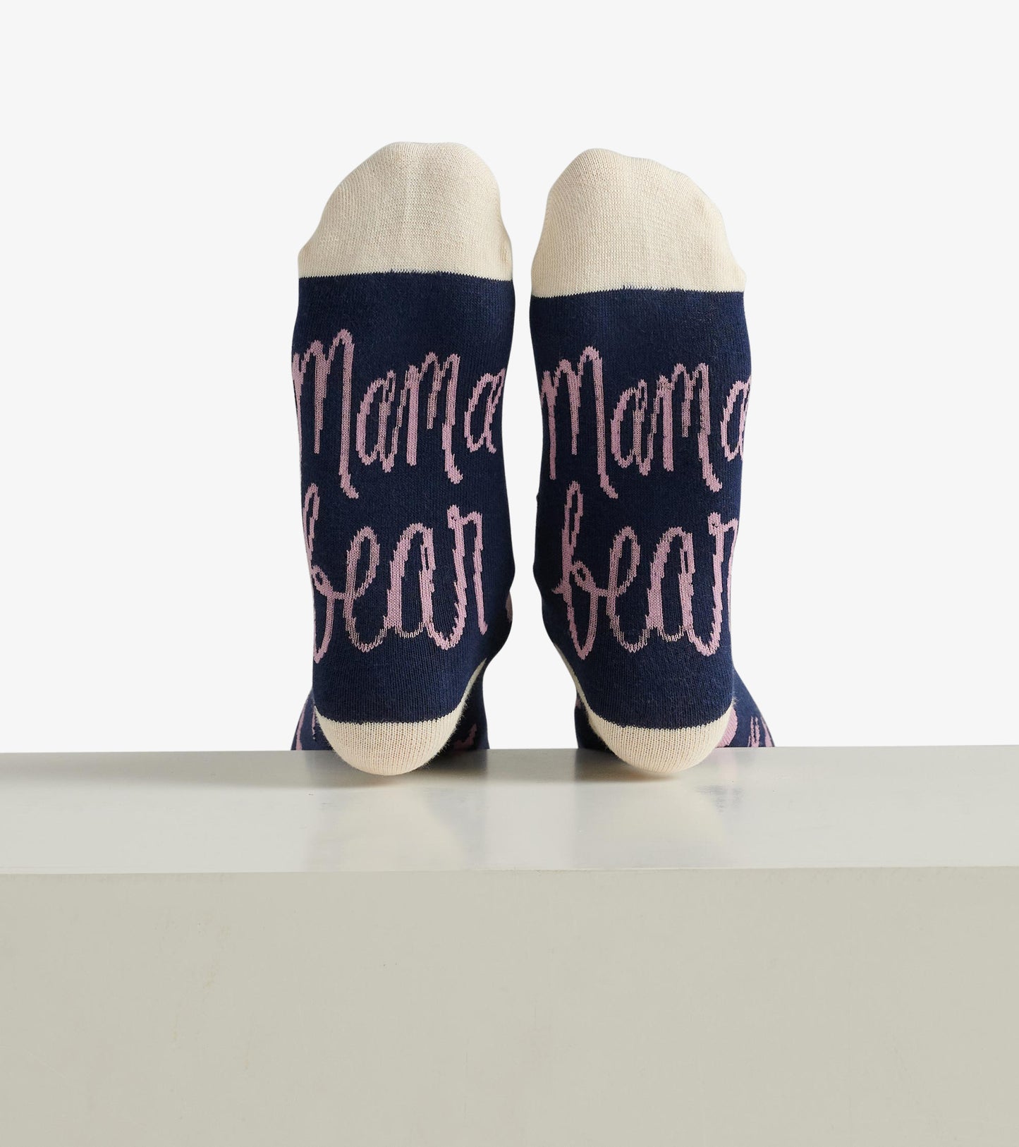 Navy crew socks with pink "Mama bear" text and cream-colored toe and heel sections.