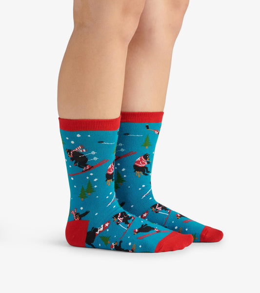 Turquoise crew socks with red cuffs, featuring playful winter-themed patterns of bears skiing and pine trees.