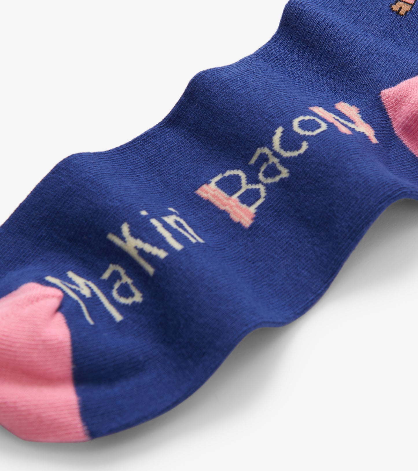 Blue crew socks featuring "Makin' Bacon" text and pink toe accents, suitable for casual wear.