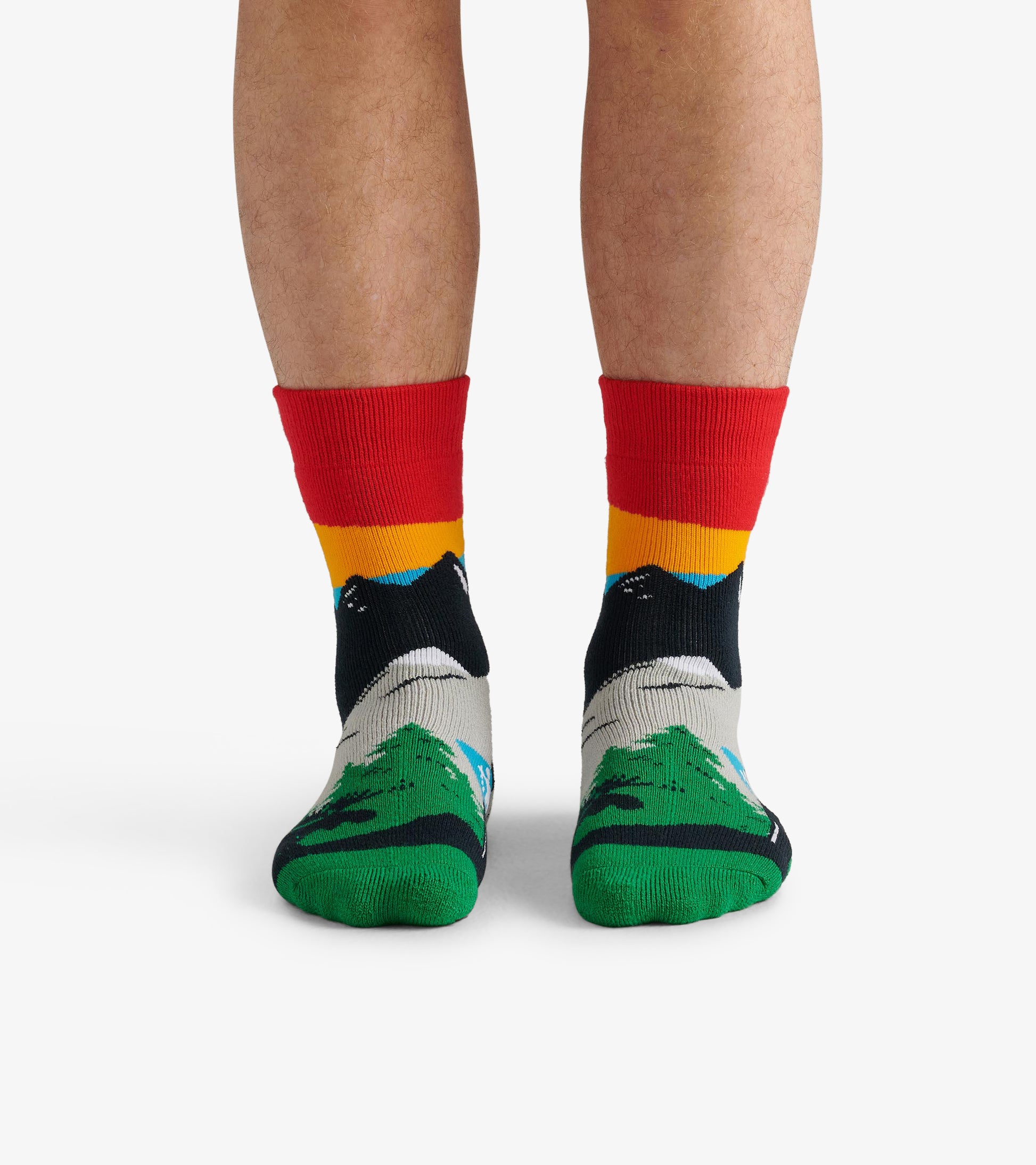 Colorful hiking socks featuring a mountain design with red, yellow, and green accents, shown on bare feet.