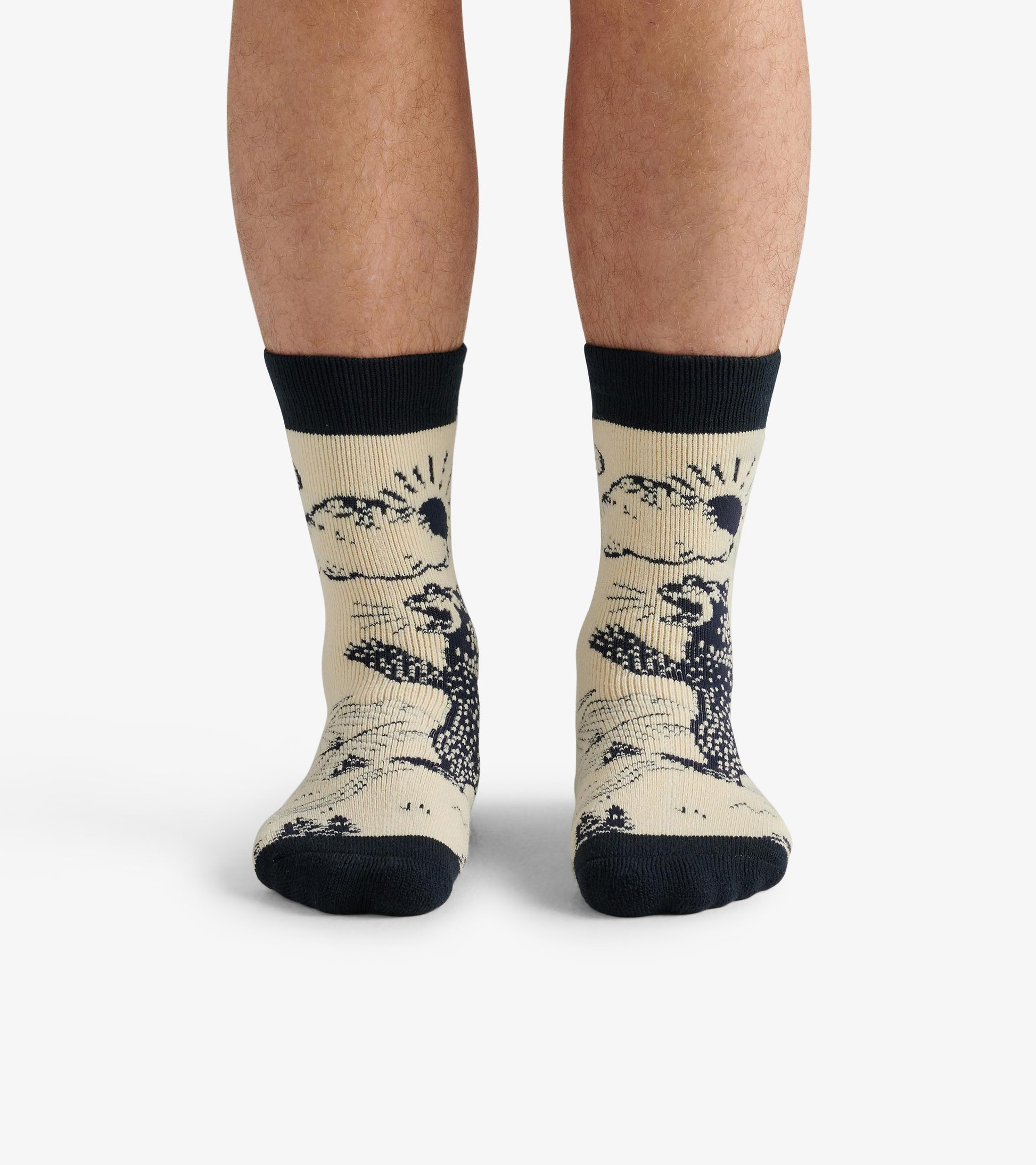 Beige cozy socks featuring a black bear design and contrasting black cuffs, worn on feet.