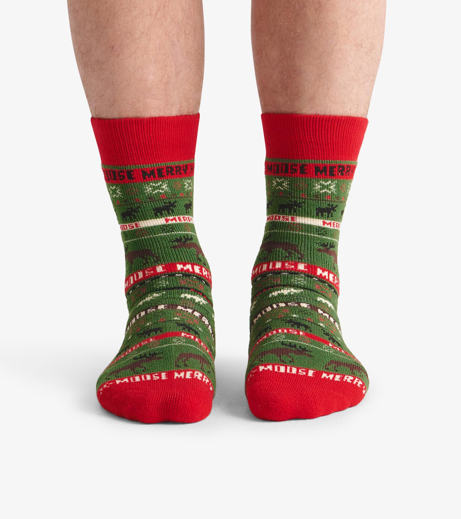 Green and red cozy socks featuring a festive moose pattern and "Merry" text, designed for comfortable wear.