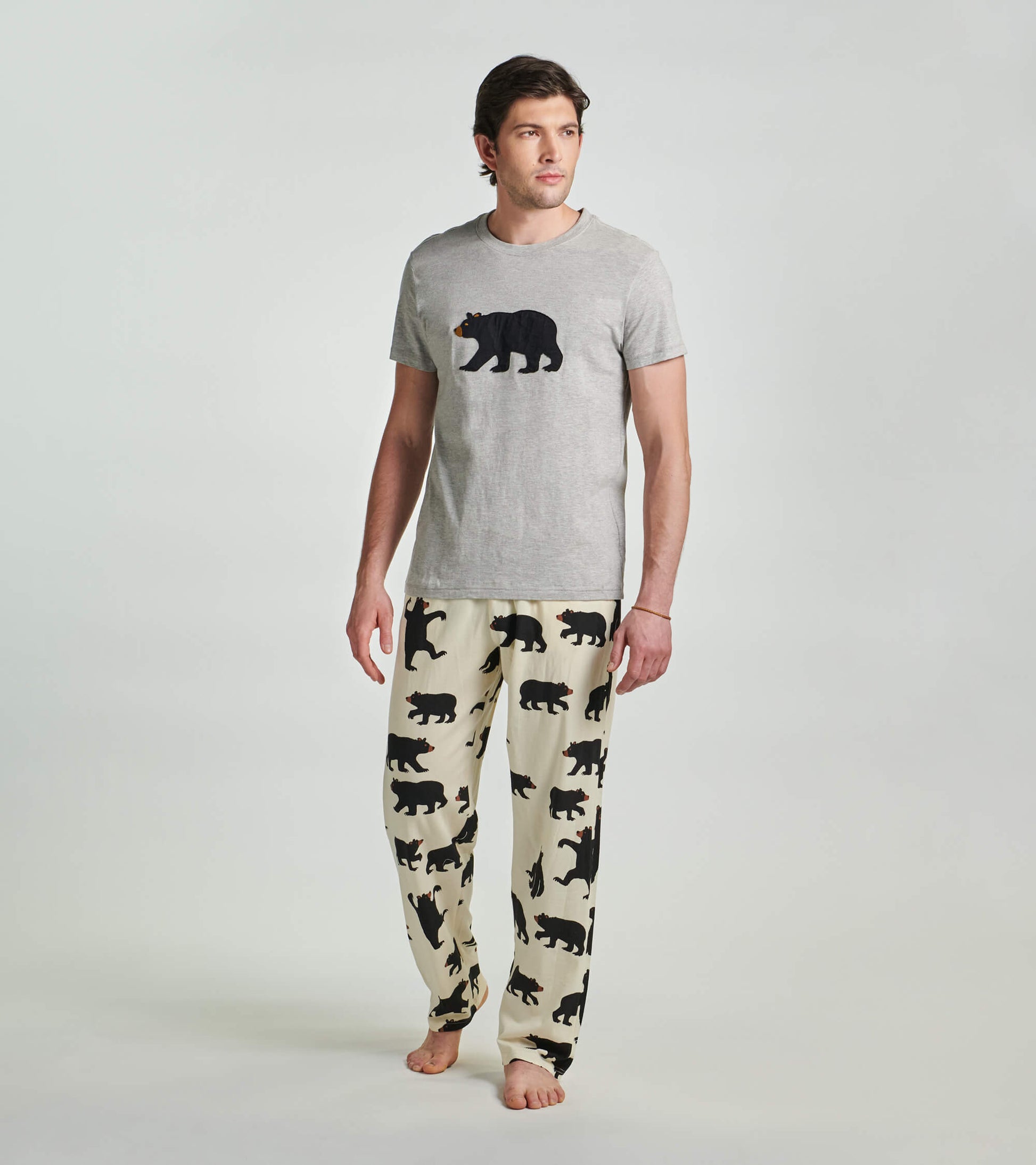 Grey men's tee featuring a black bear graphic, paired with cream pants adorned with black bear silhouettes.