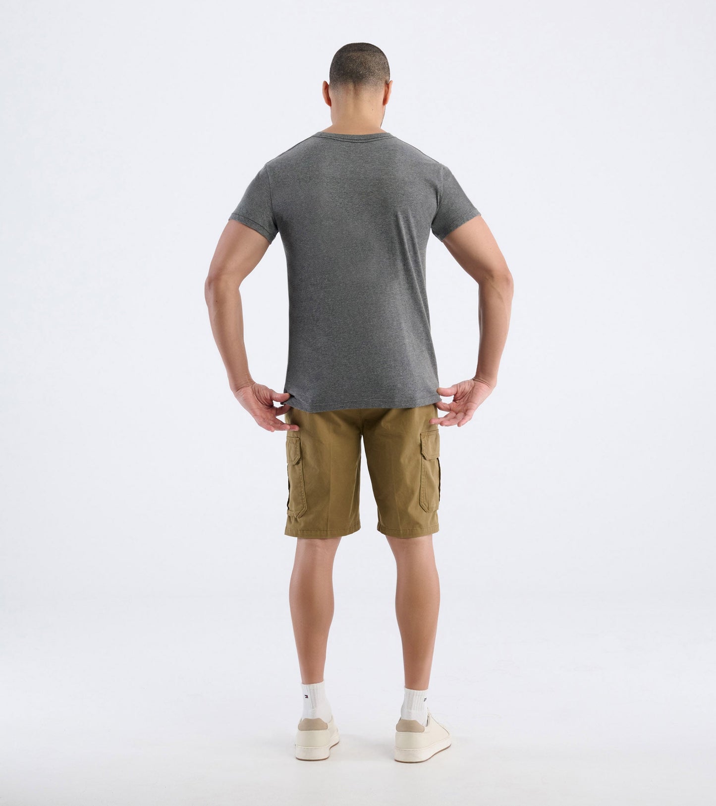 Gray short-sleeve men's tee, viewed from the back, paired with khaki cargo shorts and white socks.