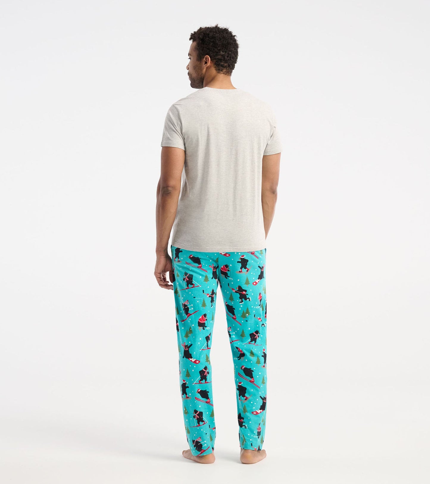 Gray short-sleeve t-shirt worn with colorful patterned pajama pants featuring skiing bears and trees, viewed from the back.