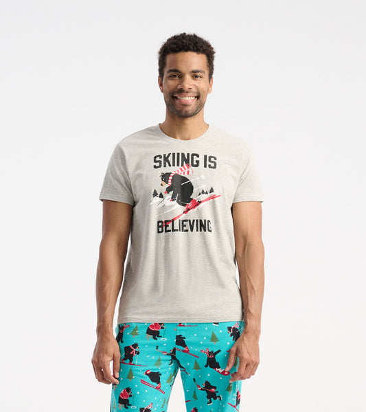 Gray short-sleeve t-shirt featuring a skiing bear graphic and the text "SKIING IS BELIEVING.