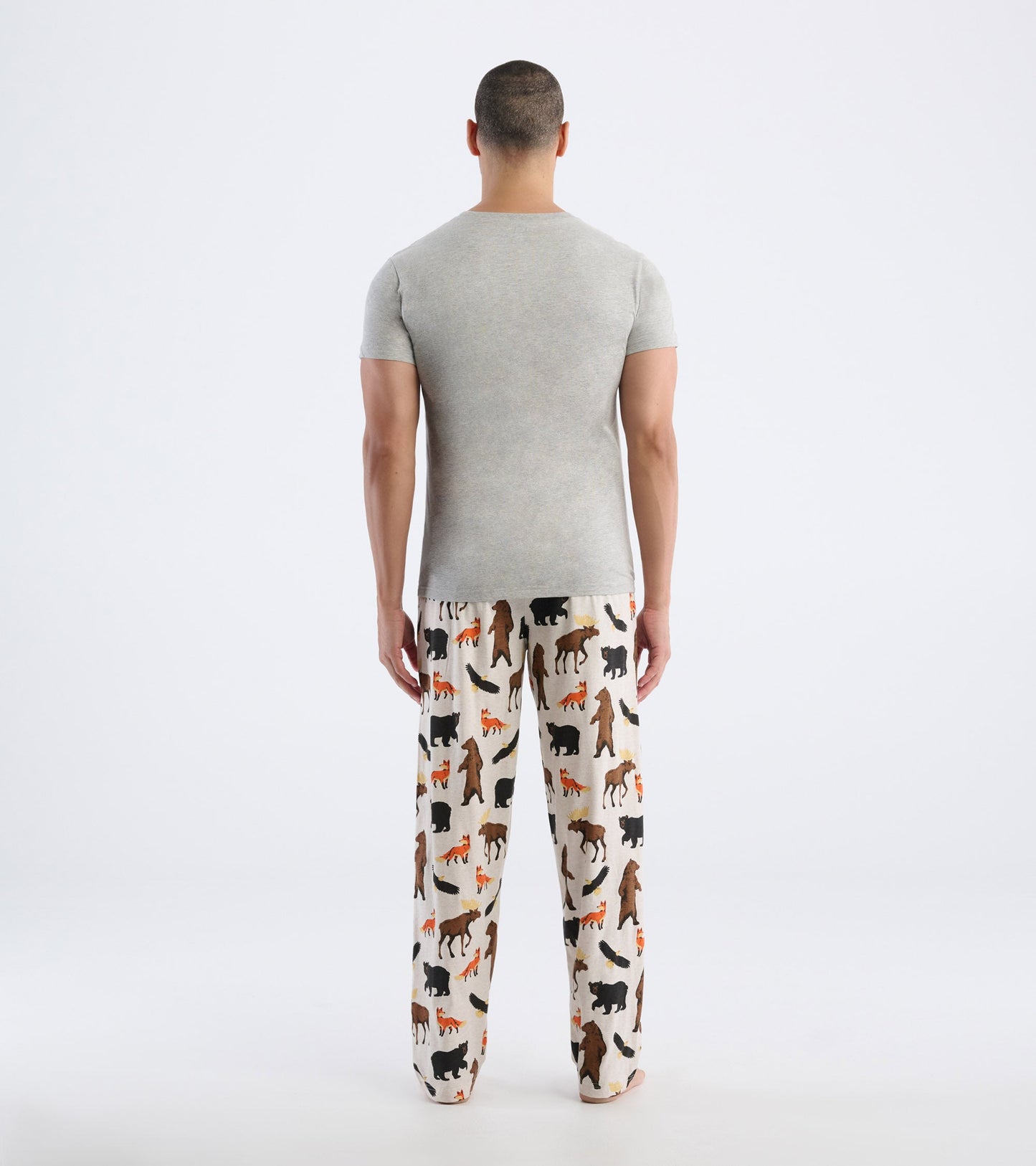 Gray short-sleeve tee worn with patterned pajama pants featuring various animal silhouettes. View from the back.