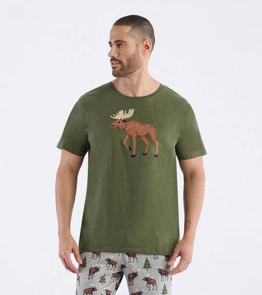 Olive green short-sleeve t-shirt featuring a moose graphic on the front, worn by a man with patterned pajama pants.
