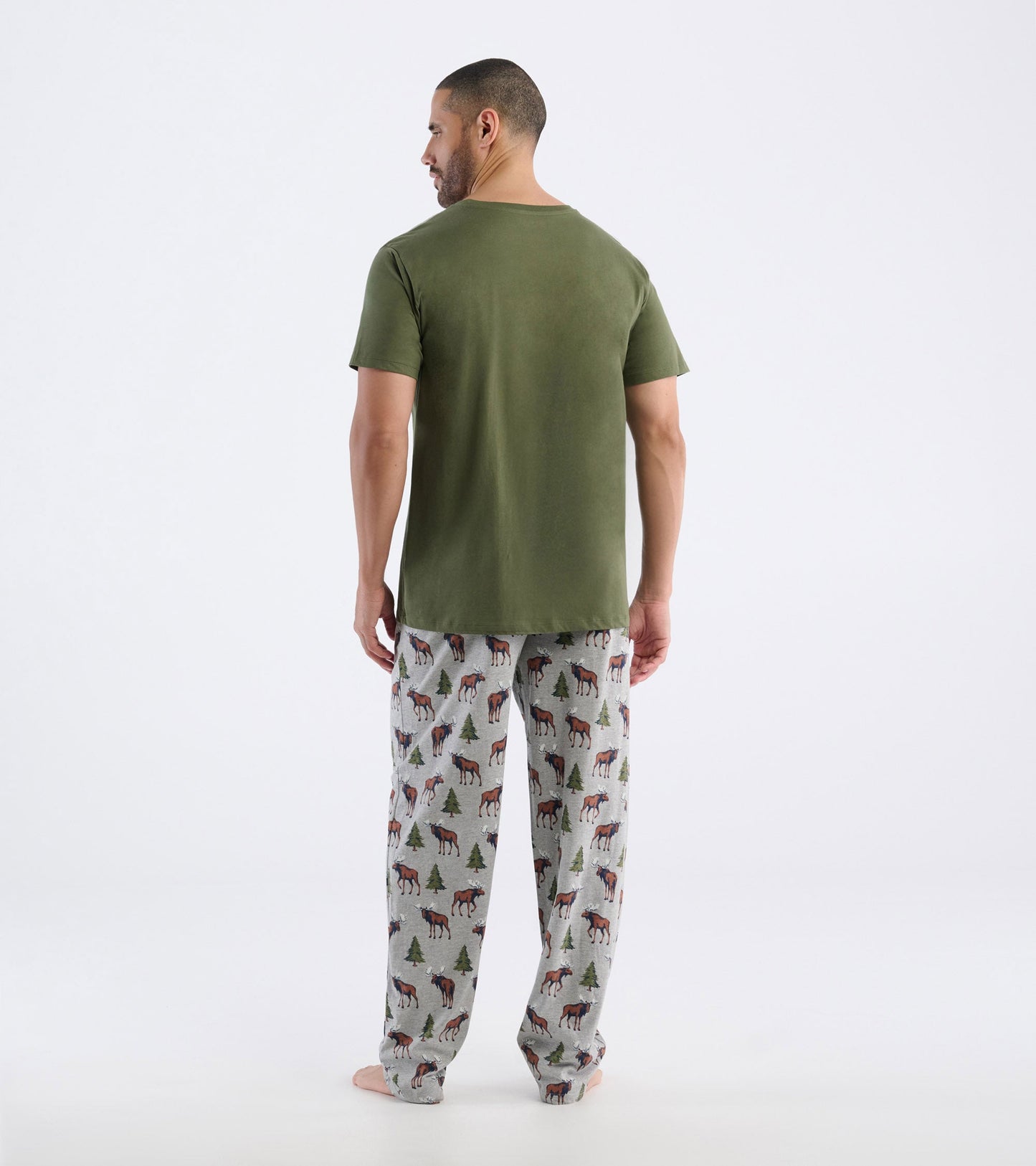 Men's olive green t-shirt paired with patterned pajama pants featuring moose and trees, shown from the back.