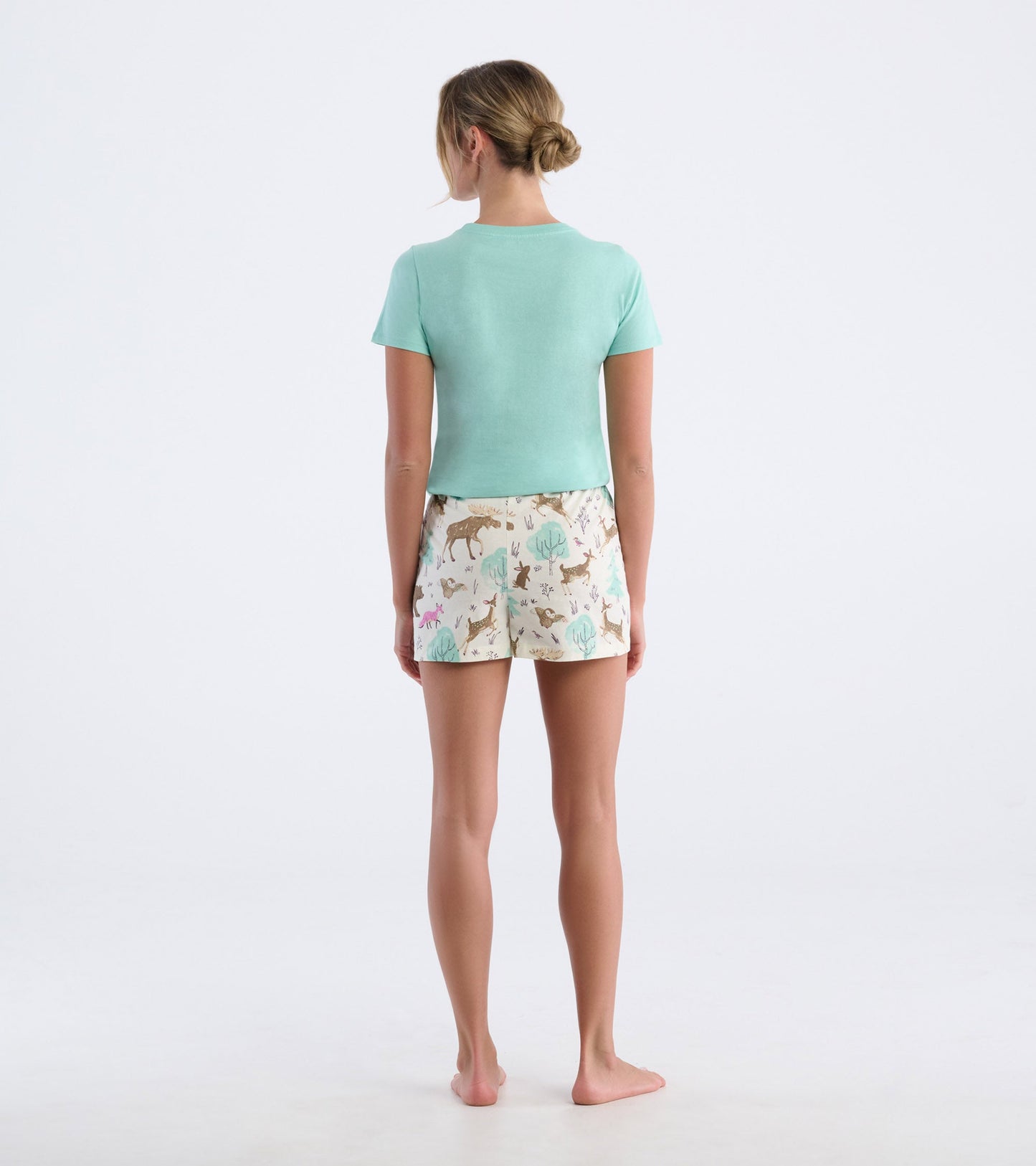 Mint green short-sleeve pajama t-shirt paired with patterned shorts featuring animals and nature motifs, viewed from the bac…