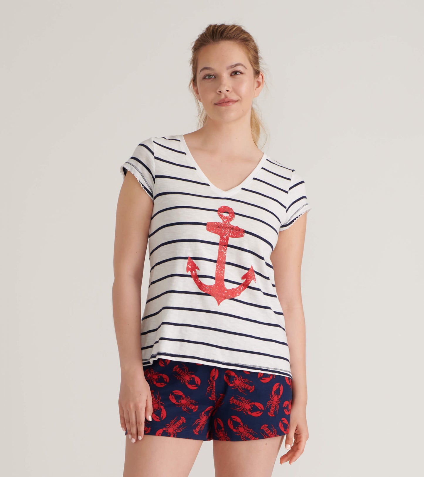 White striped V-neck tee featuring a red anchor graphic, paired with navy shorts with lobster print.