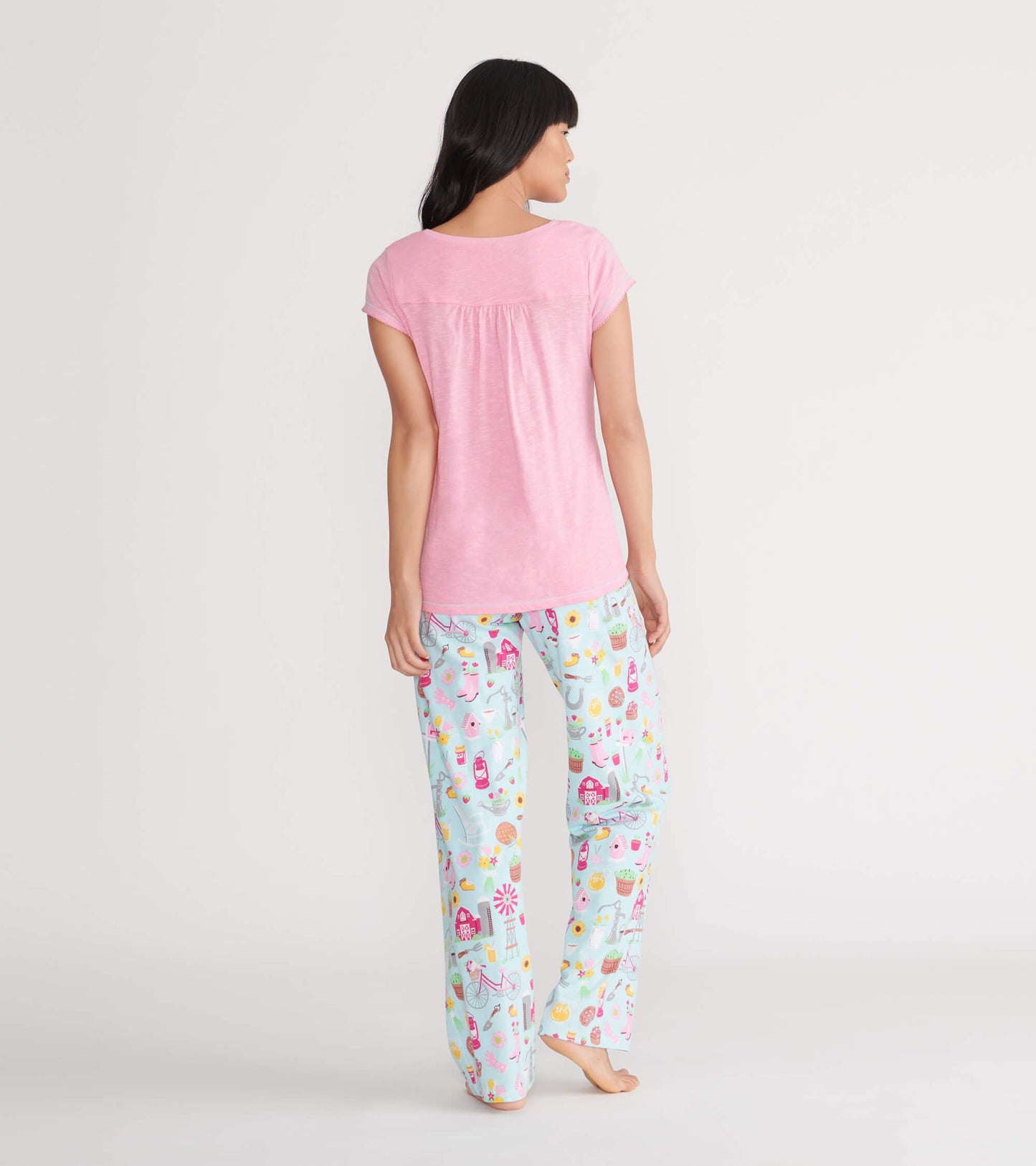 Pink V-neck tee with short sleeves, featuring a gathered back detail, paired with colorful patterned pajama pants.