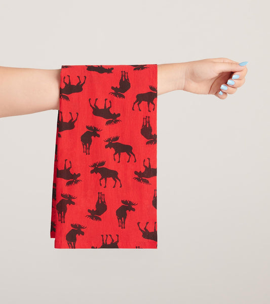 Red tea towel featuring a pattern of black moose silhouettes, held by a hand.