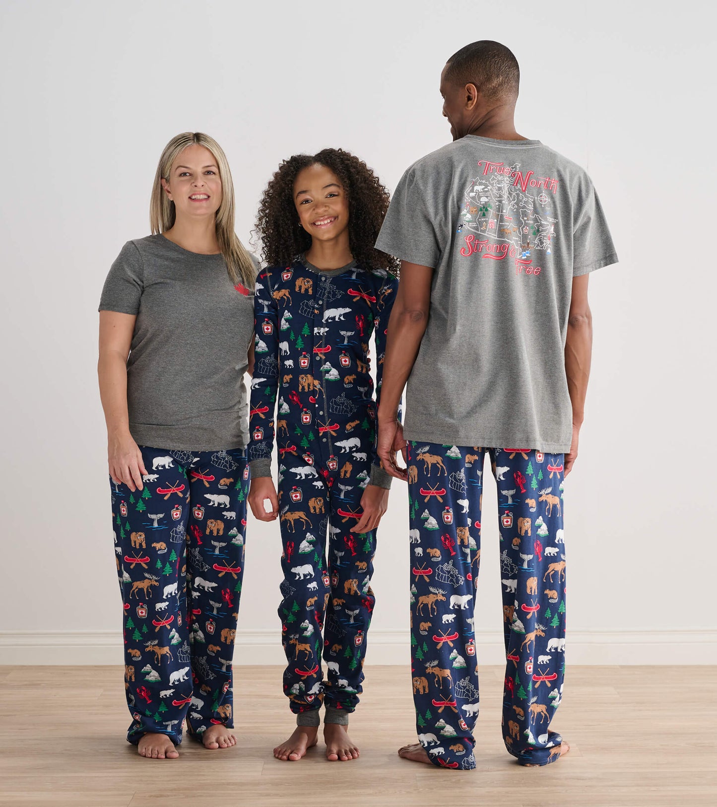 Child wearing the navy Canada-themed onesie with adults in matching pajama bottoms and gray tops
