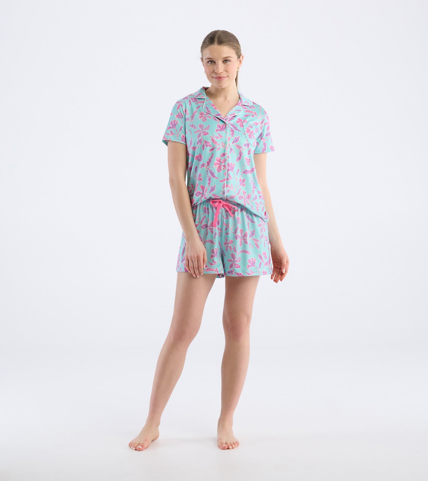 Turquoise short pajama set featuring pink batik flower patterns, with a short-sleeve top and elastic waistband shorts.