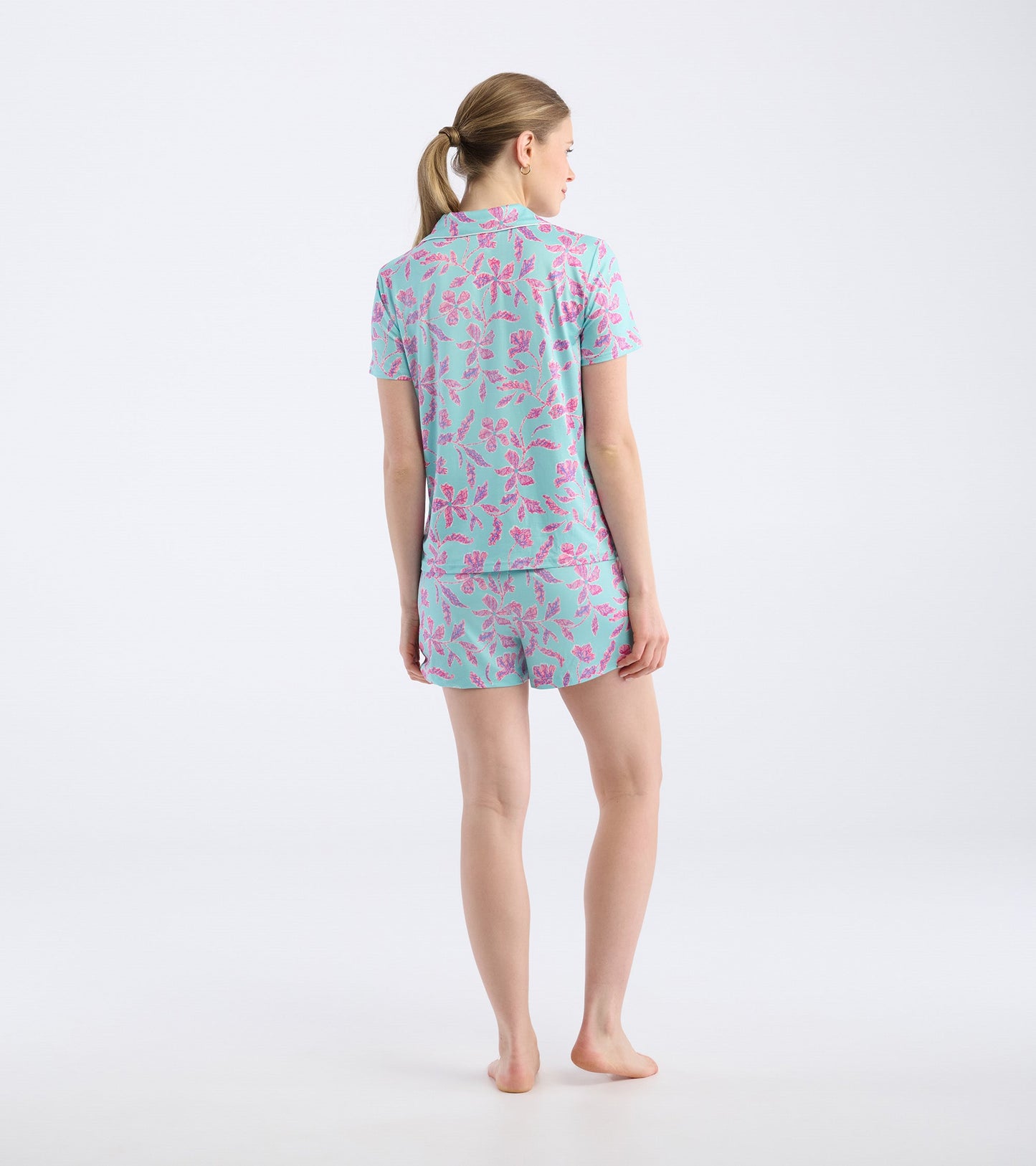 Turquoise short pajama set featuring a batik flower pattern, with a short-sleeve top and matching shorts, viewed from the ba…