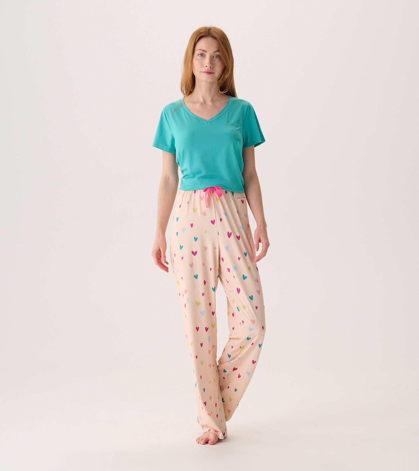 Turquoise V-neck T-shirt paired with light pink pajama pants featuring colorful heart patterns.