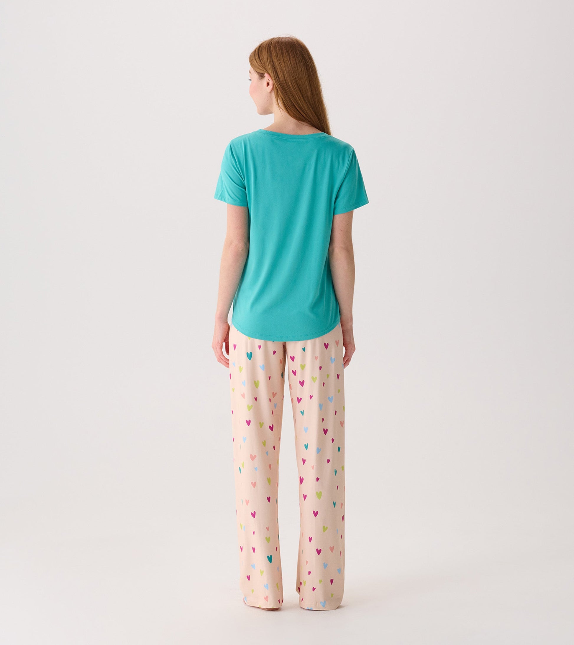 Turquoise V-neck T-shirt with short sleeves, worn with patterned pajama pants featuring colorful hearts.