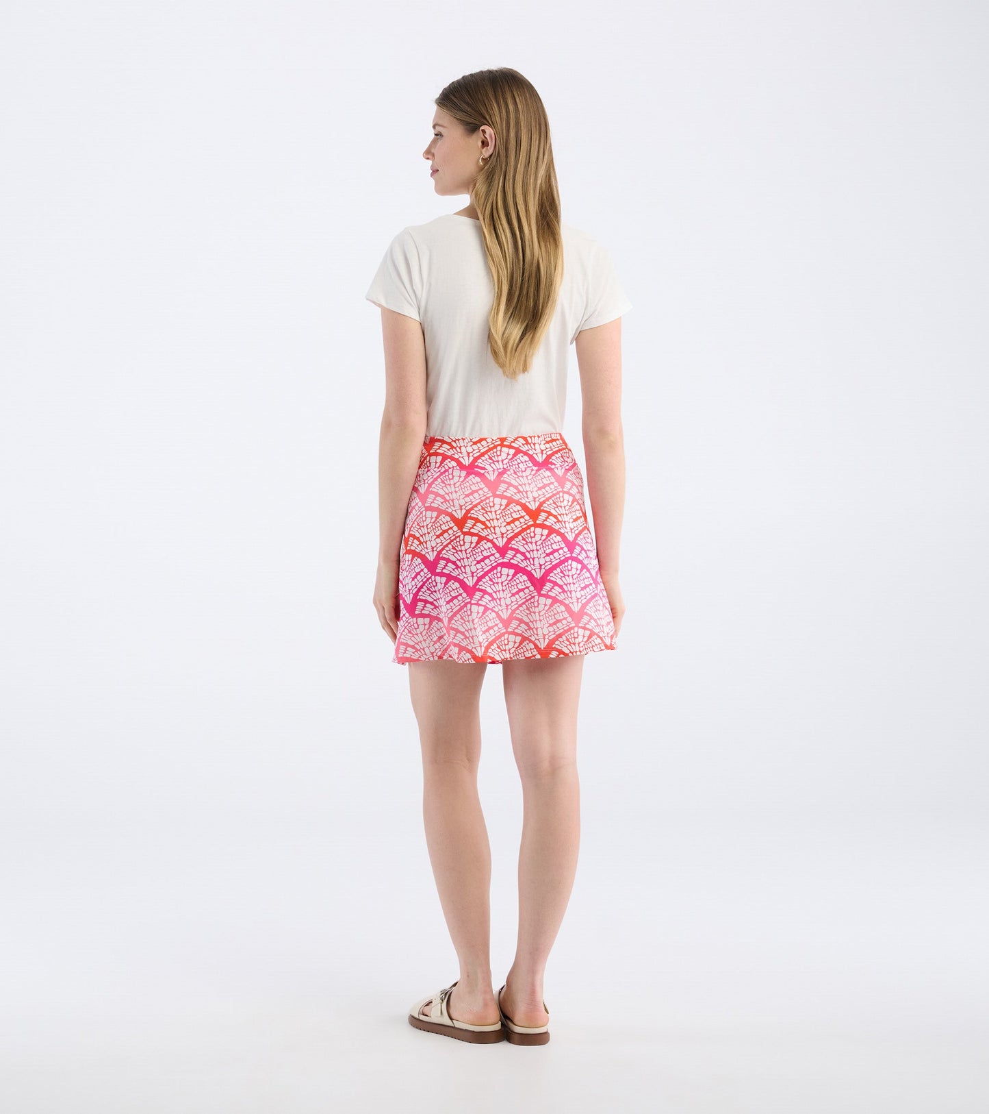 Back view of a women's skort featuring a colorful leaf pattern in pink and orange tones.