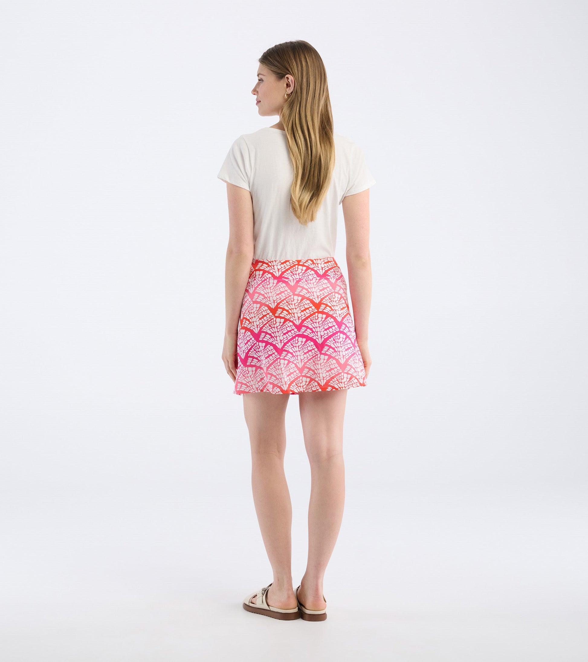 Back view of a women's skort featuring a colorful leaf pattern in pink and orange tones.